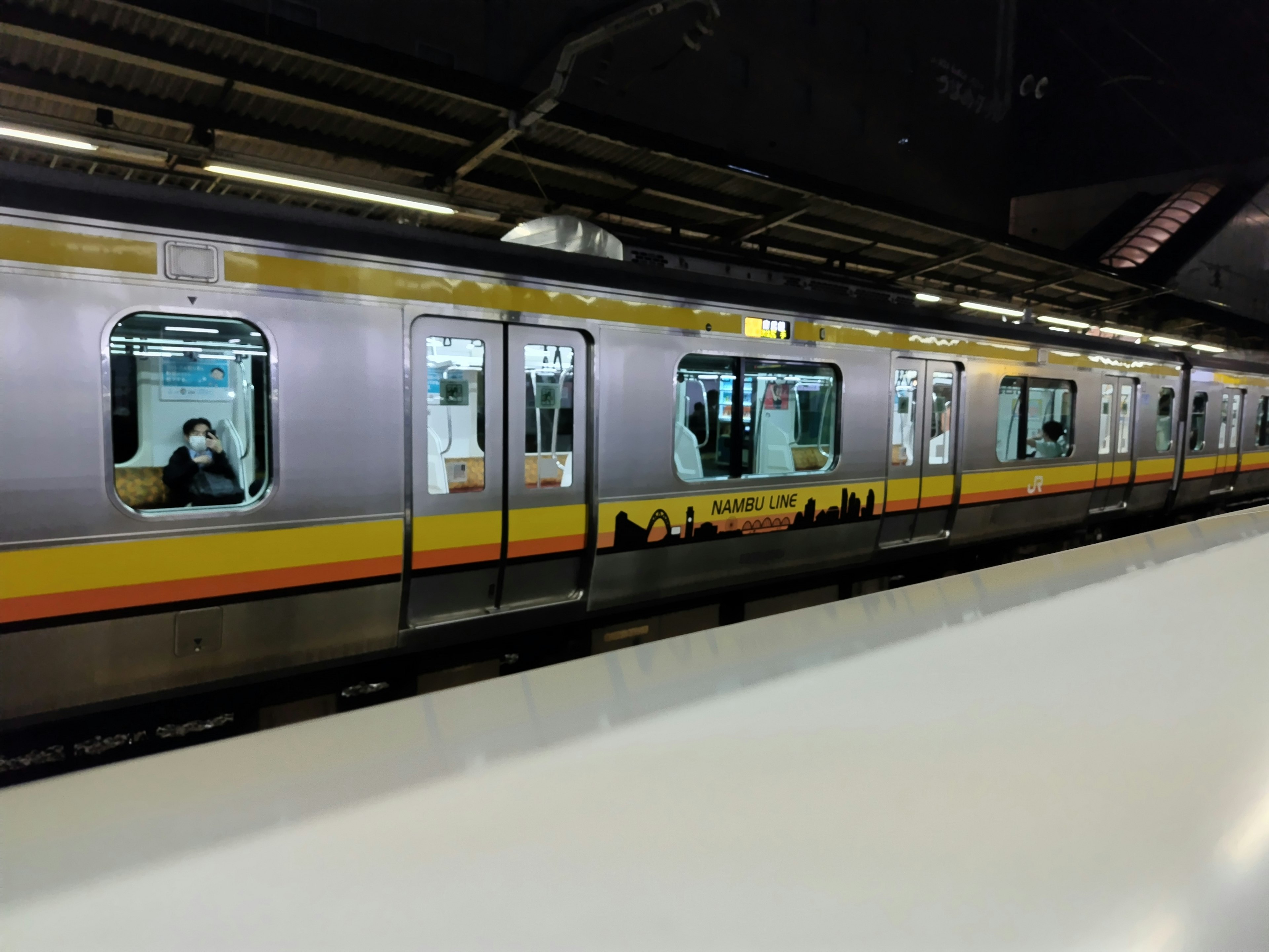 Un tren de metro estacionado en una plataforma con pasajeros visibles en las ventanas