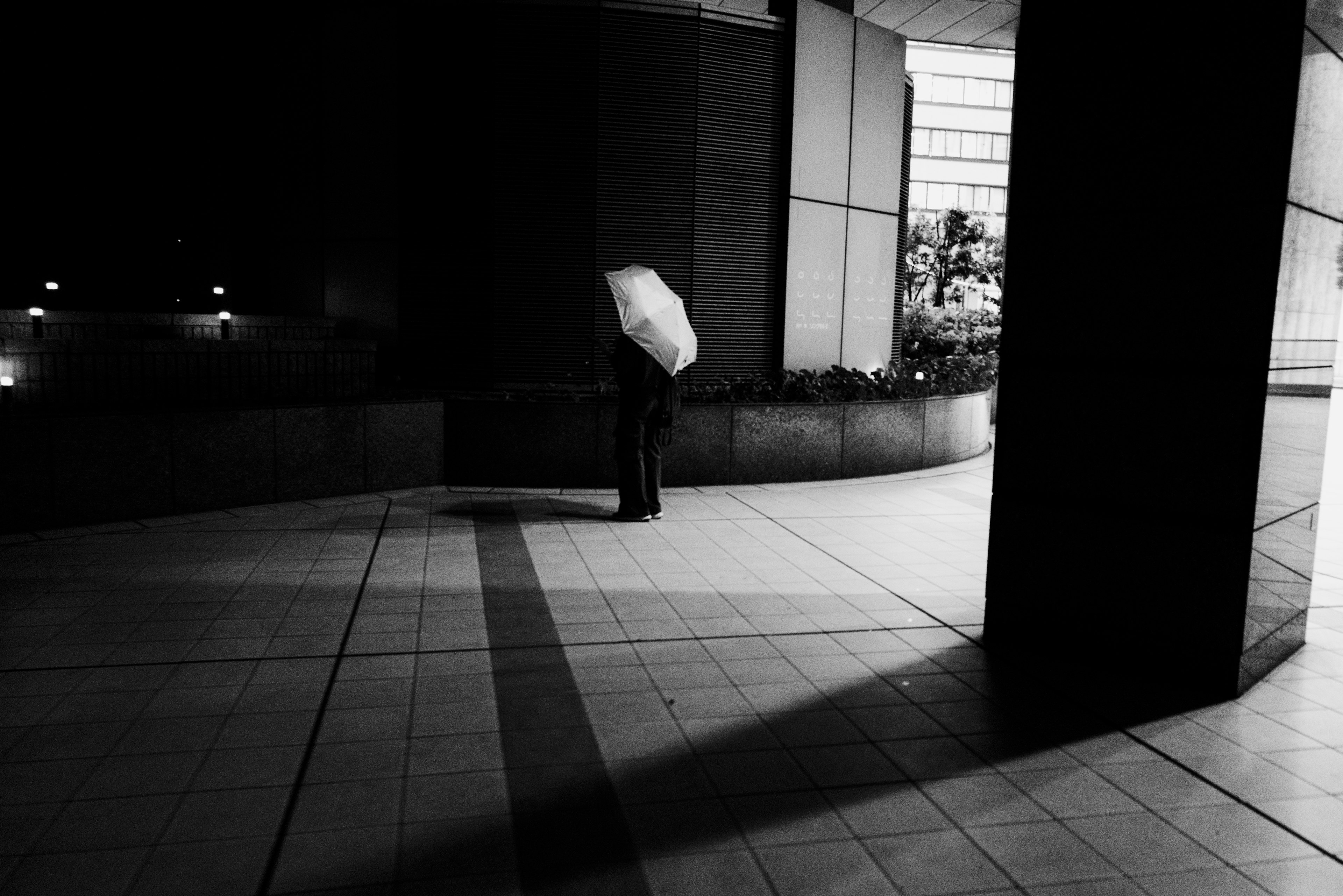 A person holding an umbrella standing in a nighttime urban setting