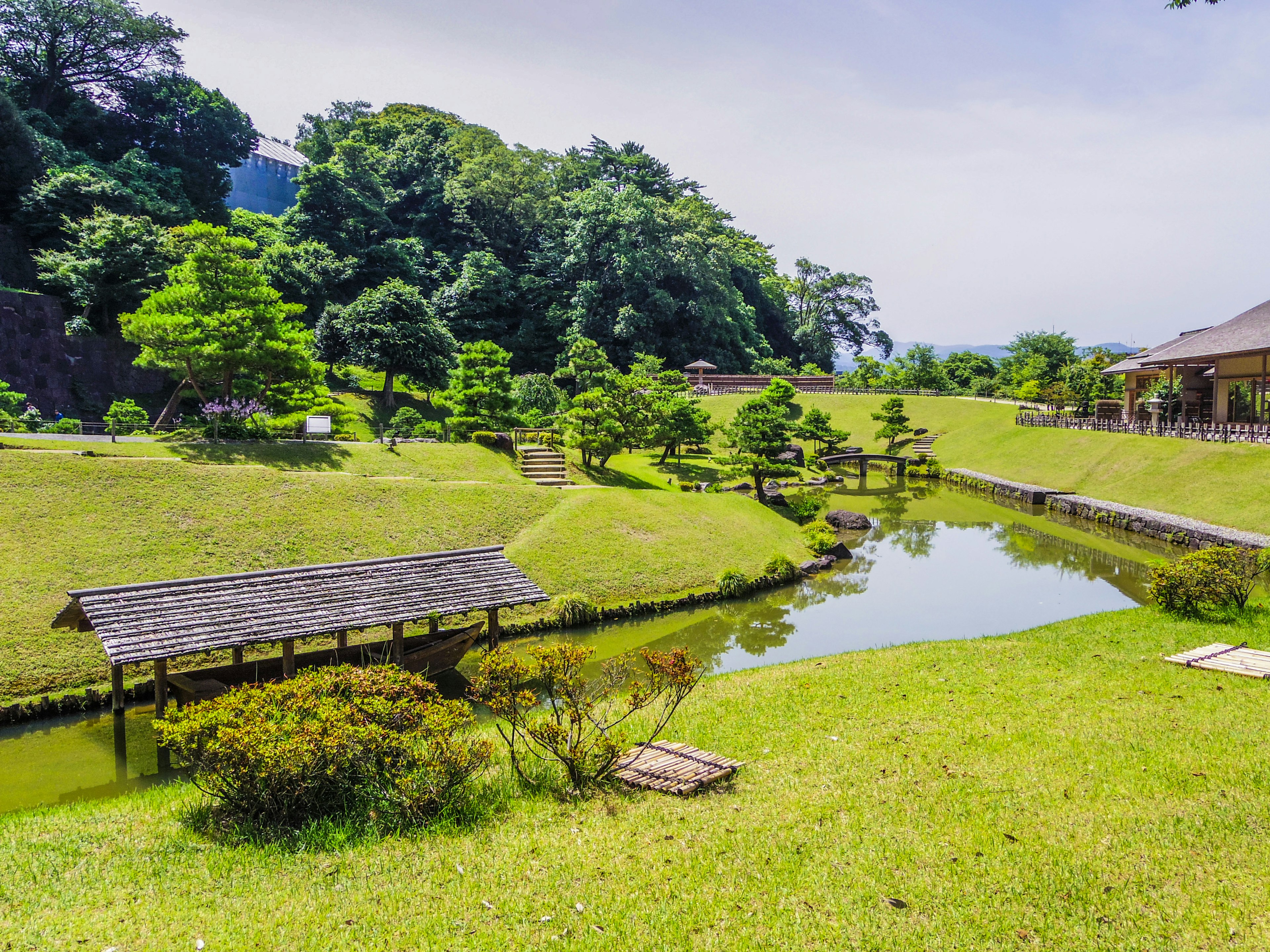 Paesaggio di giardino lussureggiante con un lago sentieri e un ponte di legno