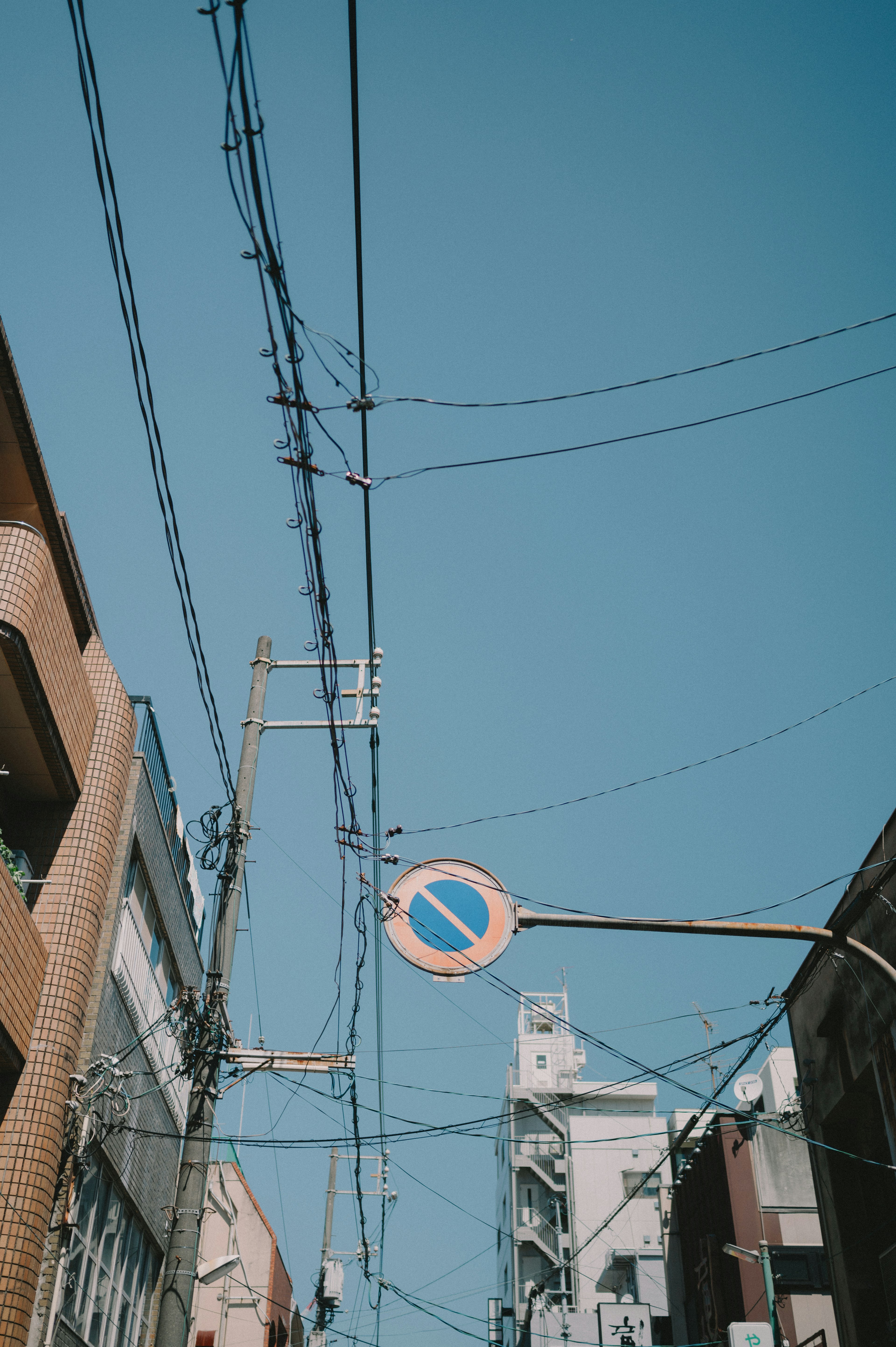 Cables eléctricos y señal de prohibido el paso bajo un cielo azul