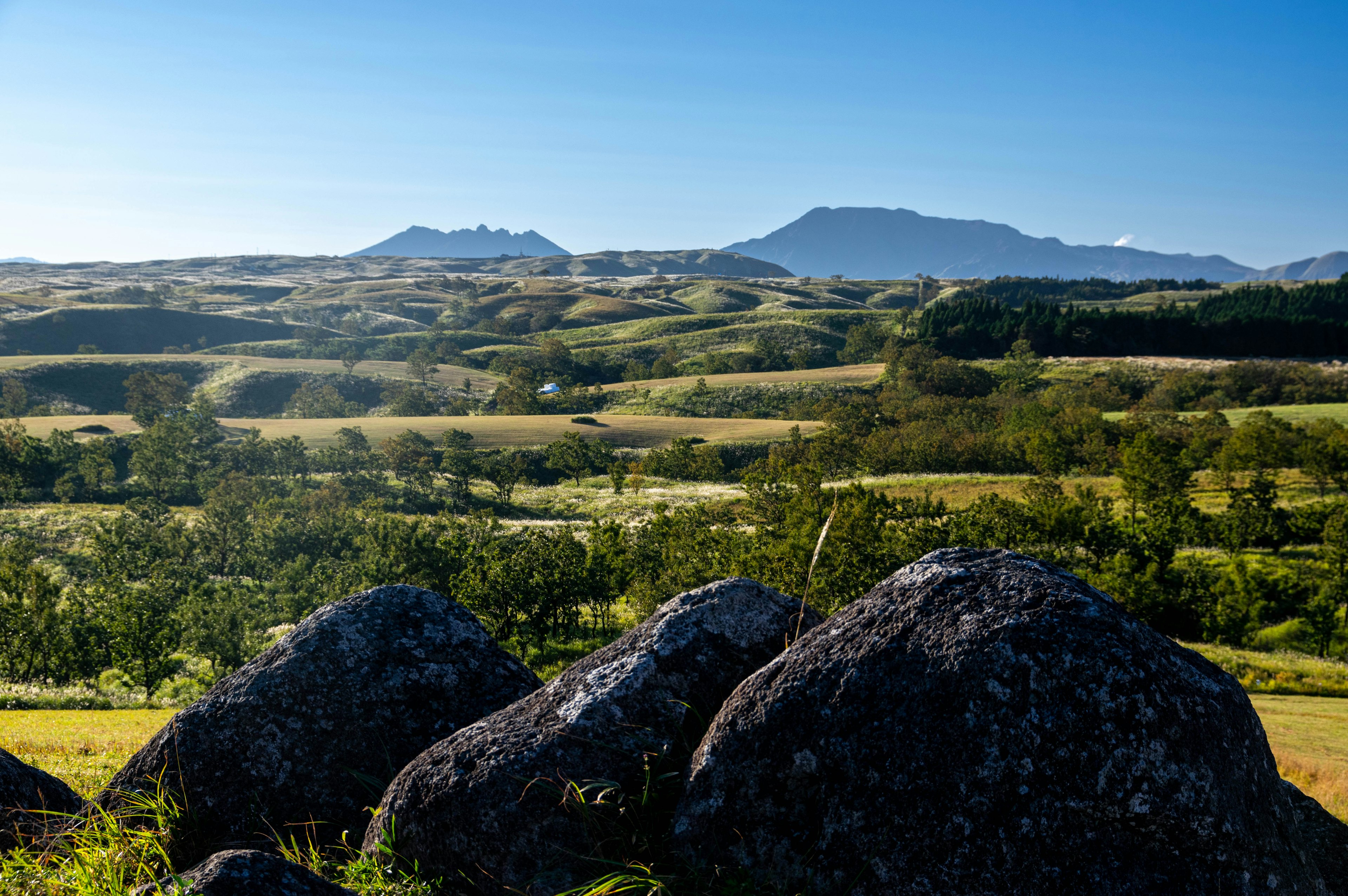 Paisaje verde vibrante bajo un cielo azul con grandes rocas