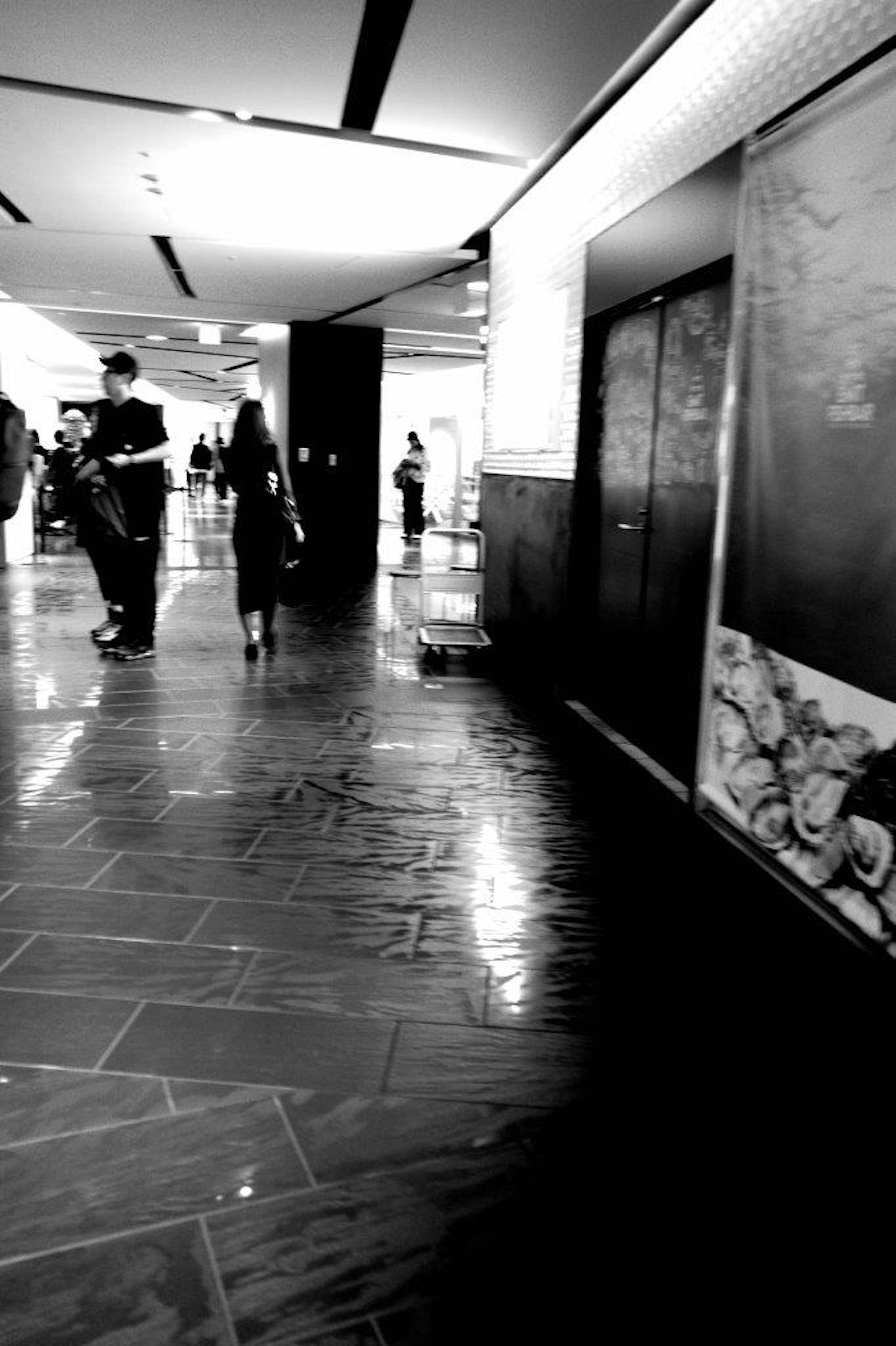 Black and white corridor with people walking