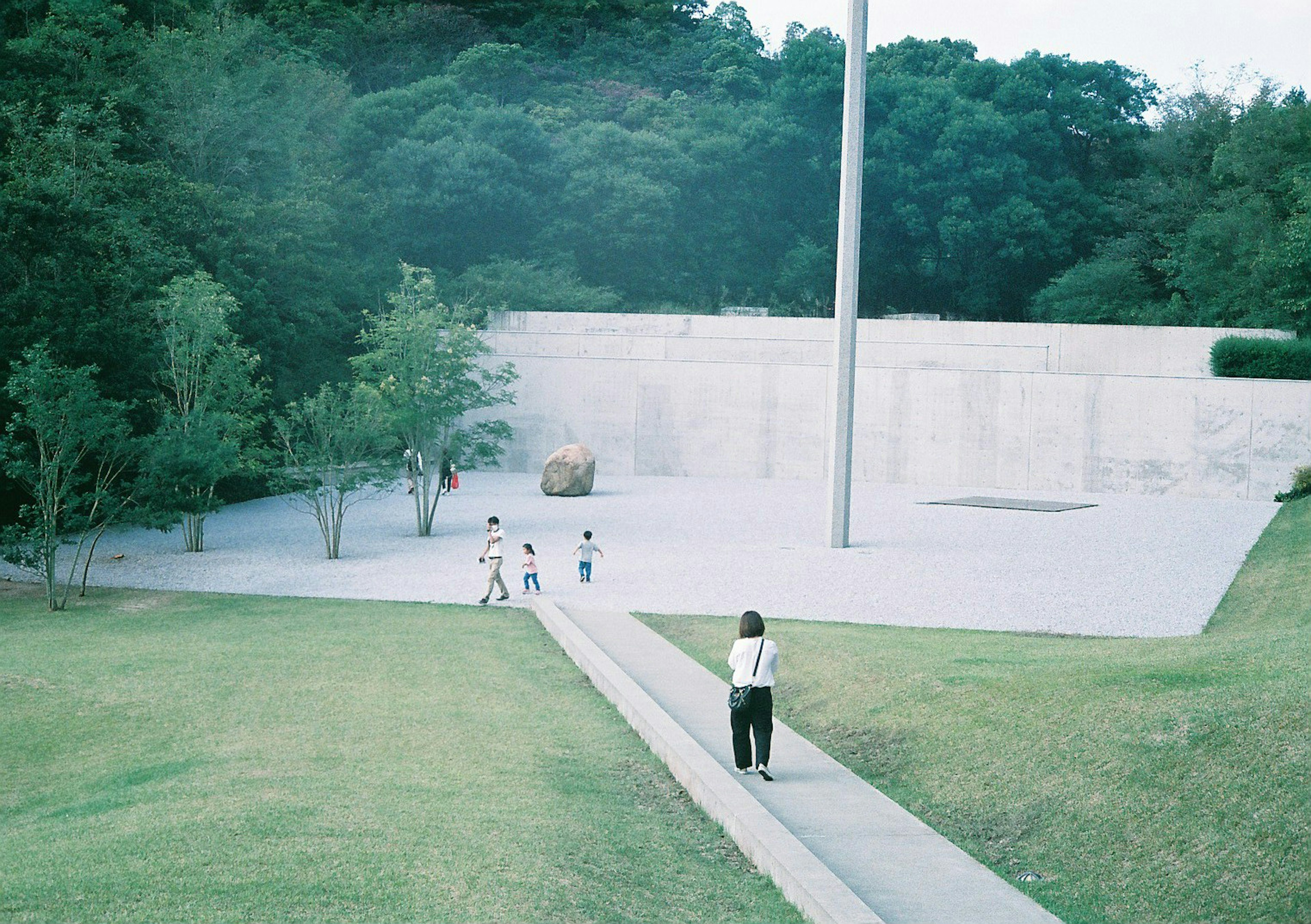 Park scene with people walking and green trees in the background