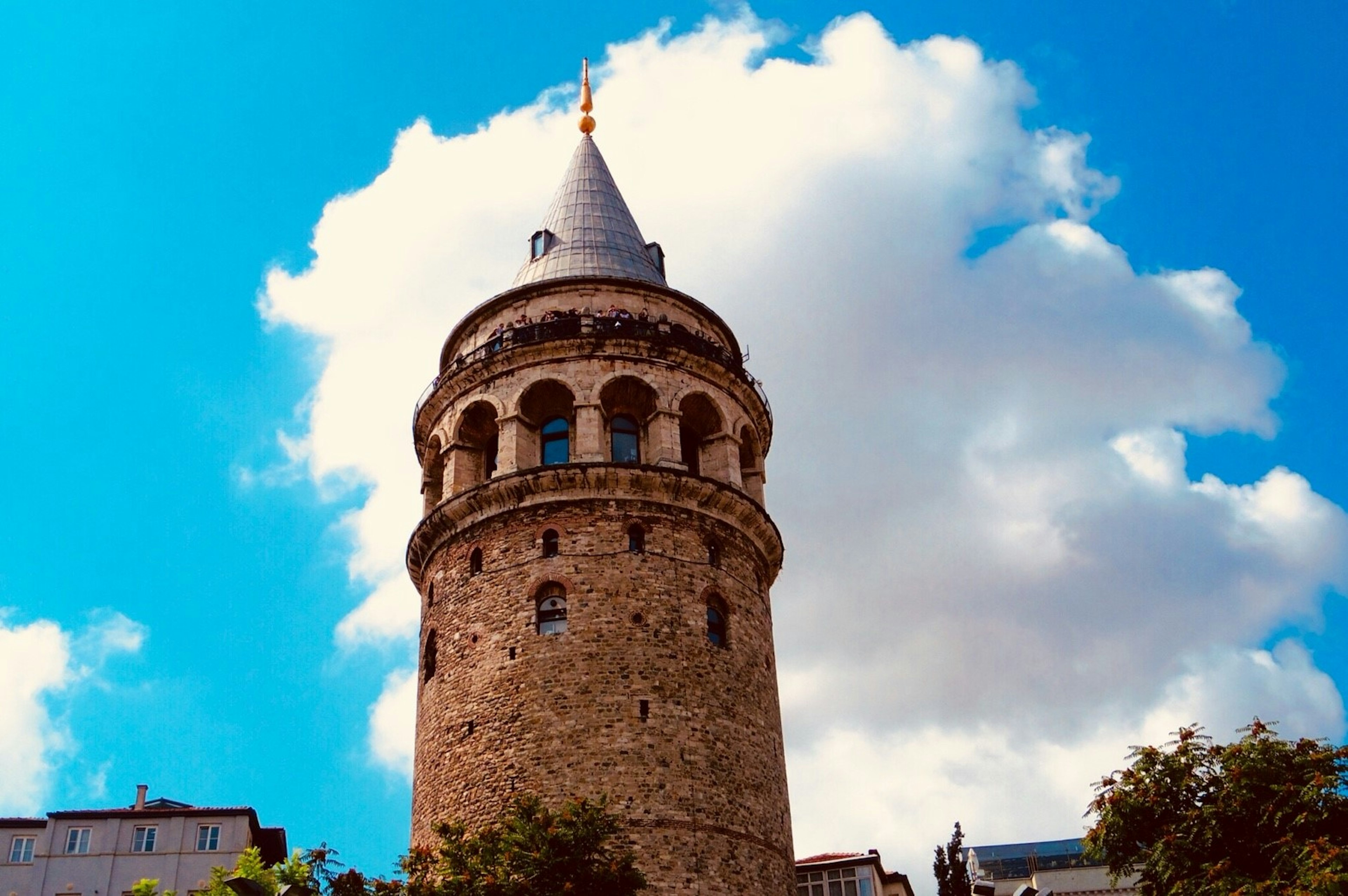 Galata Tower under a blue sky with fluffy clouds