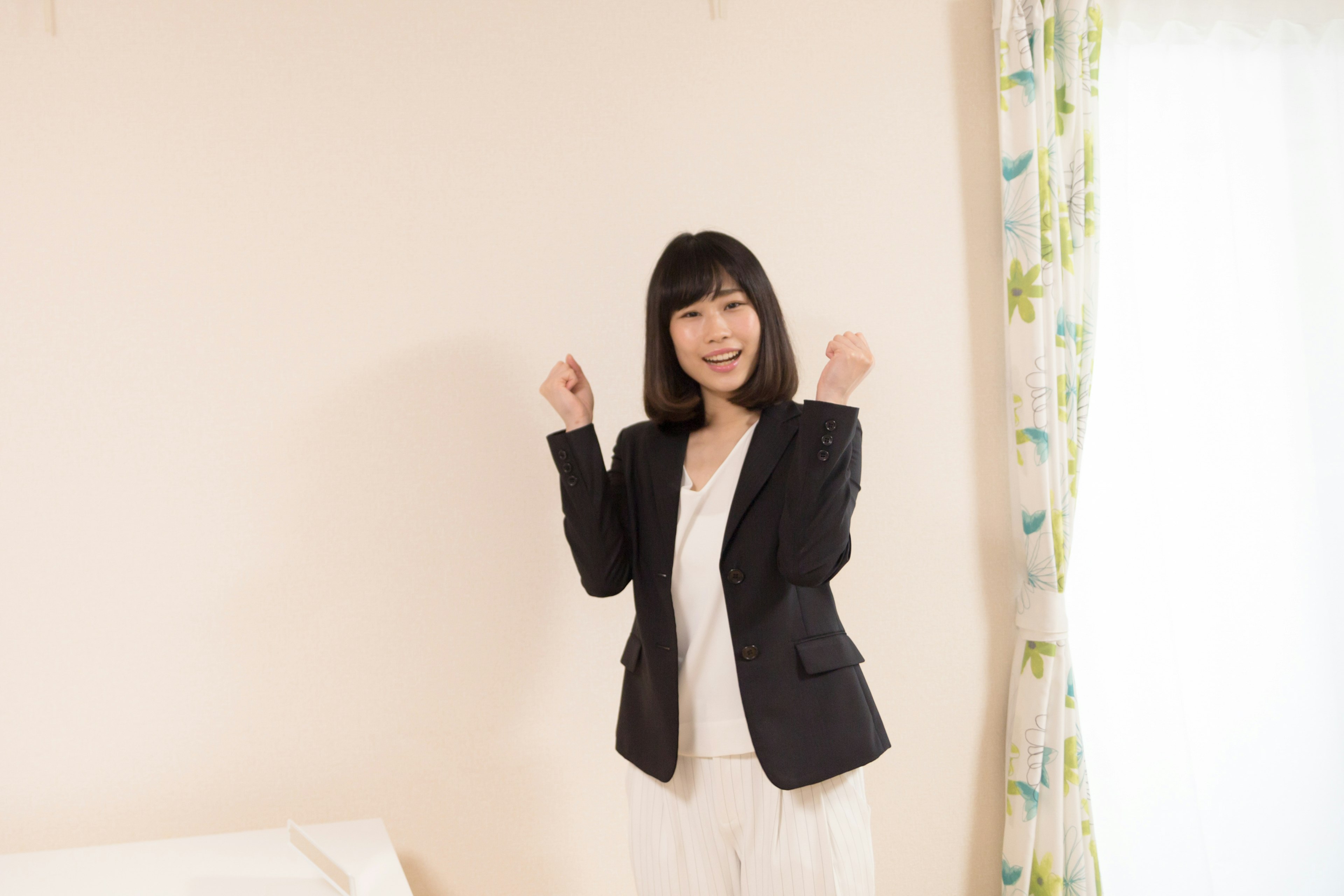 A woman in a suit smiling and posing in a room