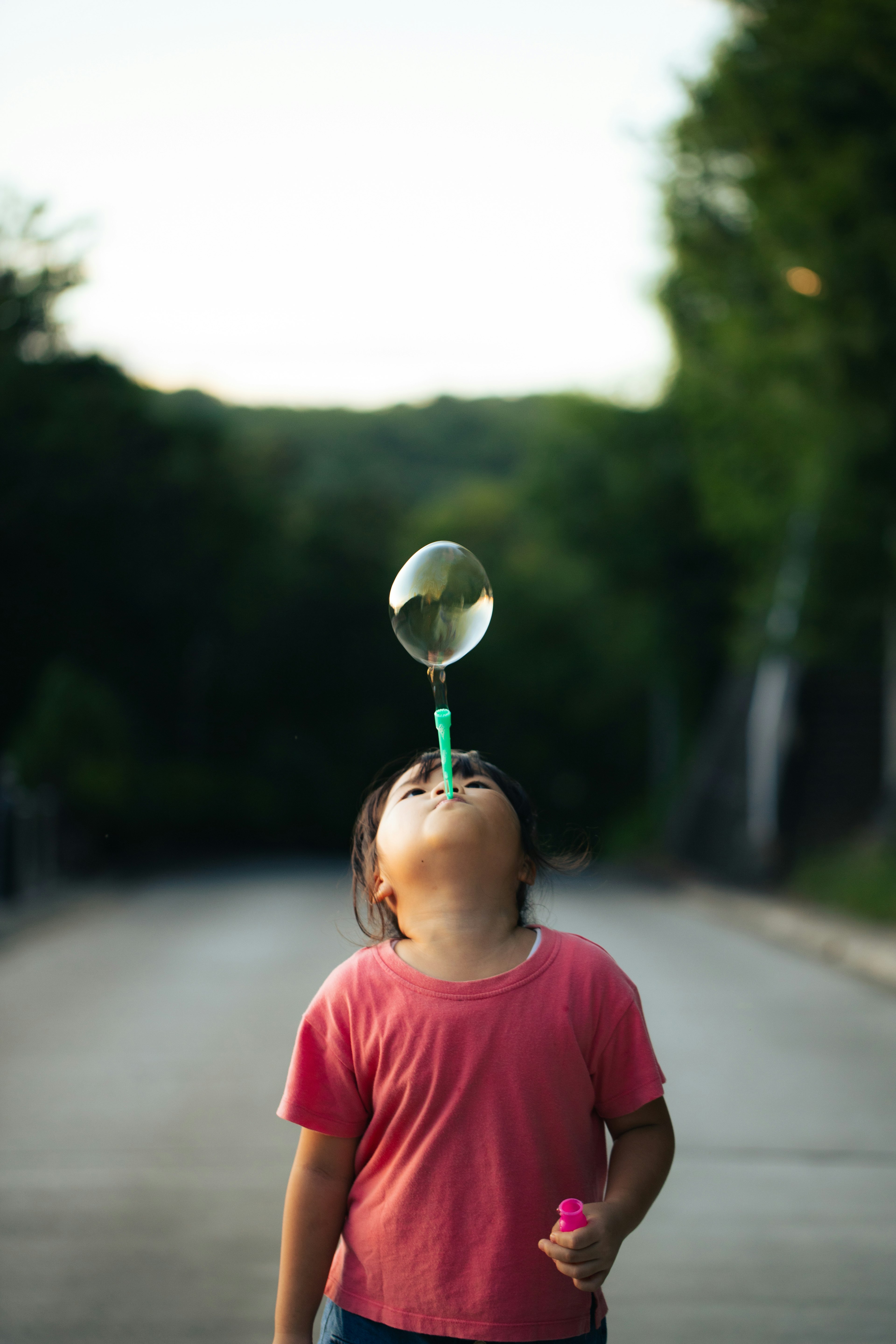 Enfant soufflant une bulle avec une paille à l'extérieur