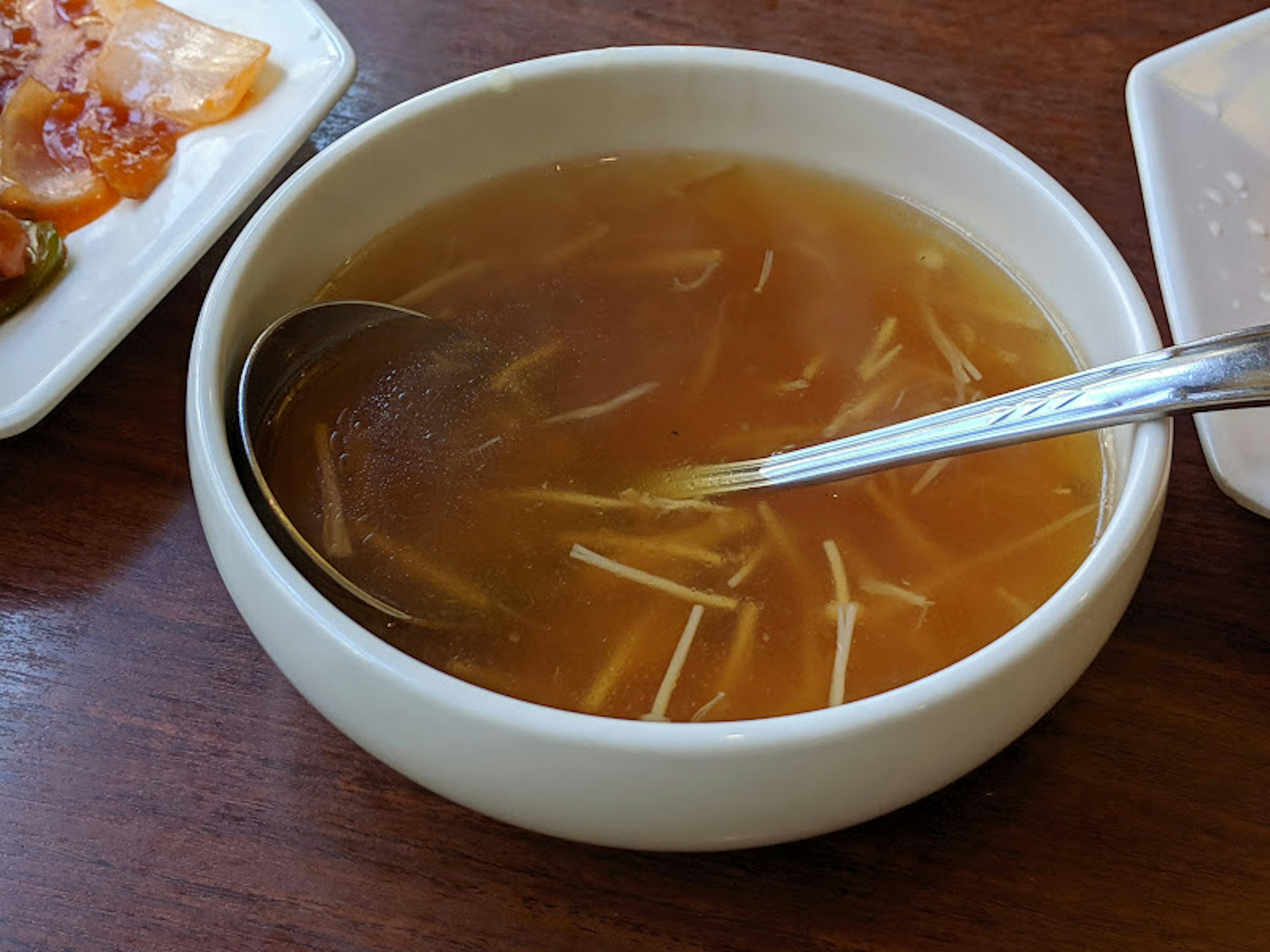 Bowl of clear soup with thinly sliced ingredients