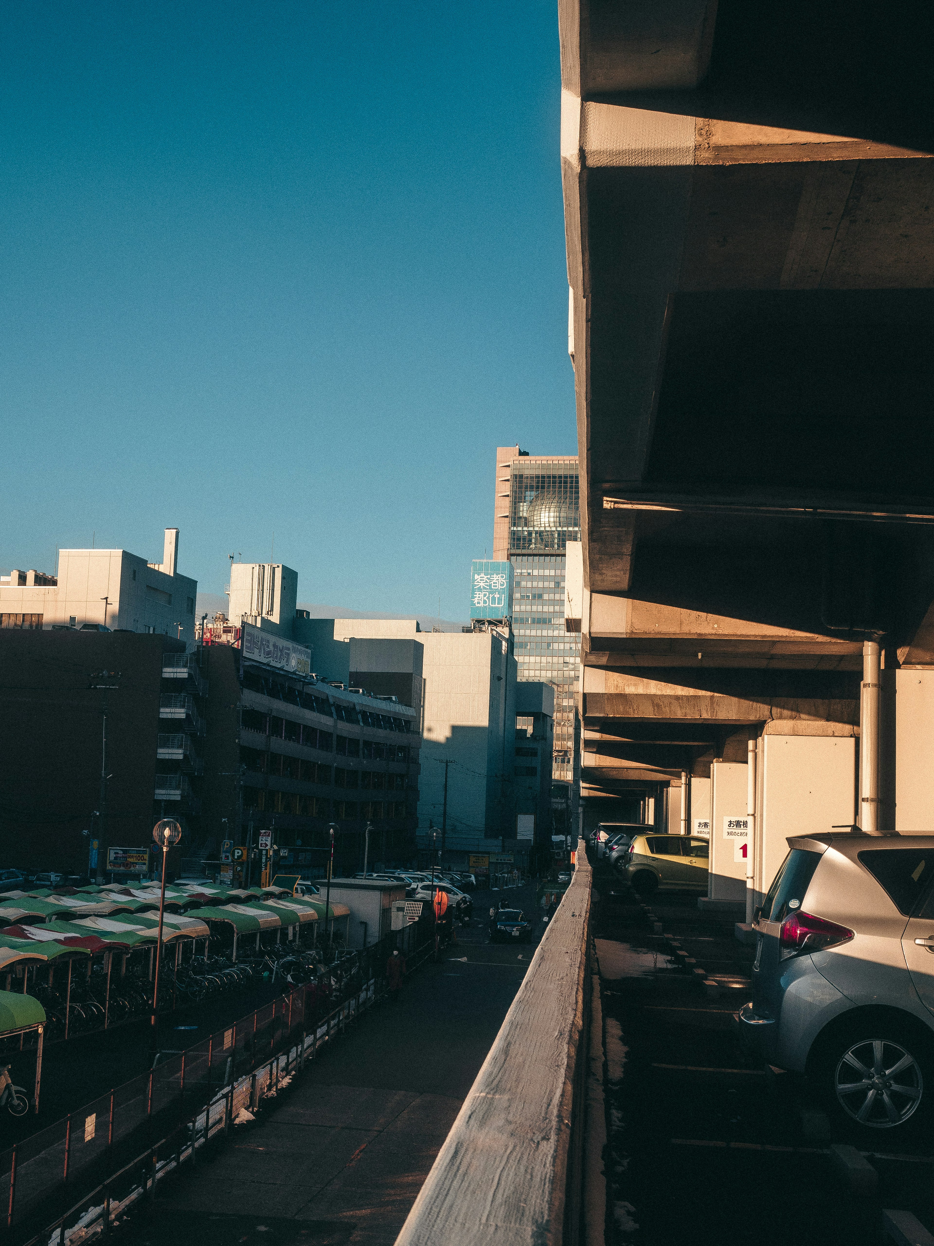 Paisaje urbano bajo un cielo azul con un estacionamiento y edificios