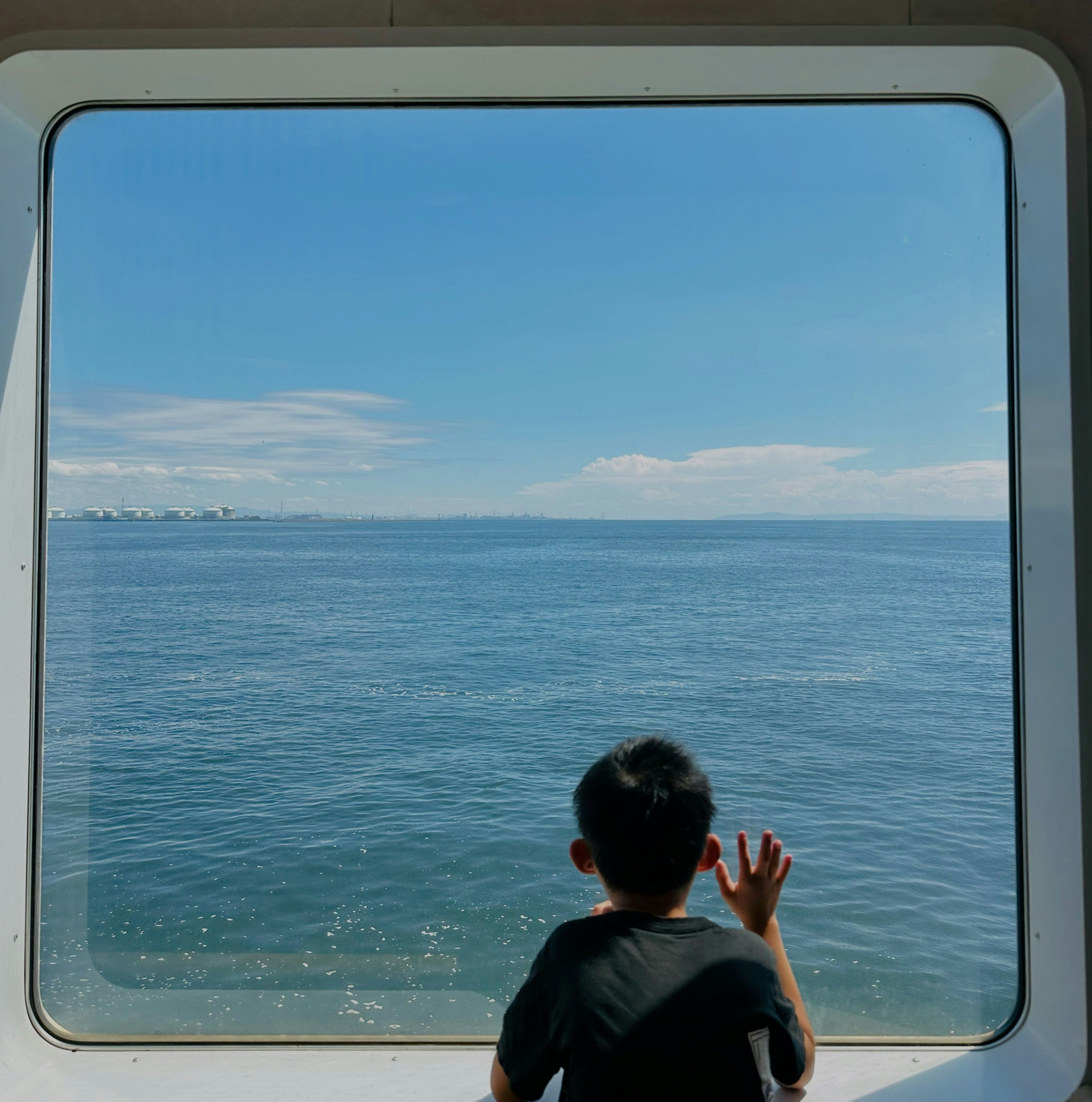 A child looking out at the ocean through a window