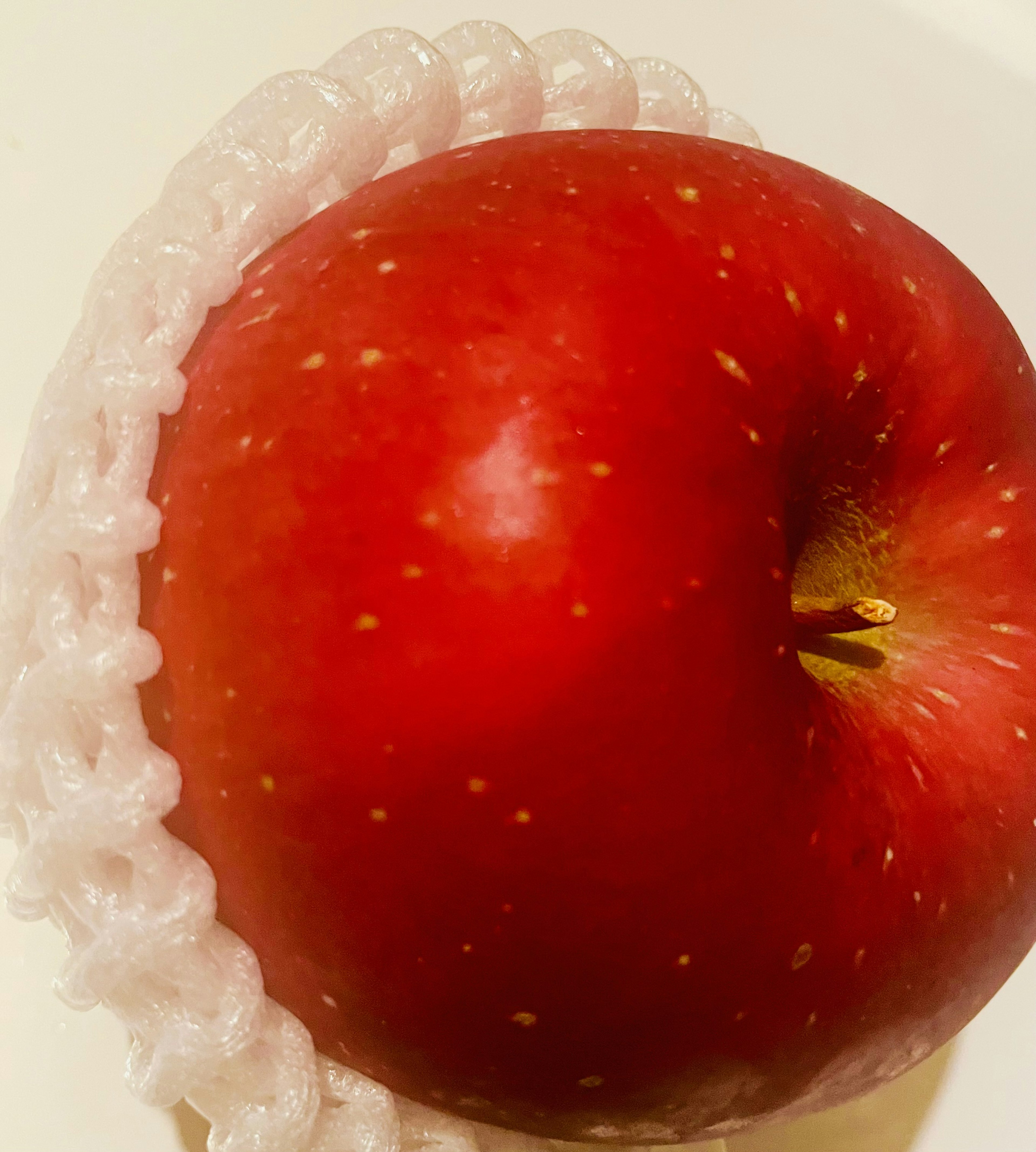 Pomme rouge entourée d'un emballage plastique blanc