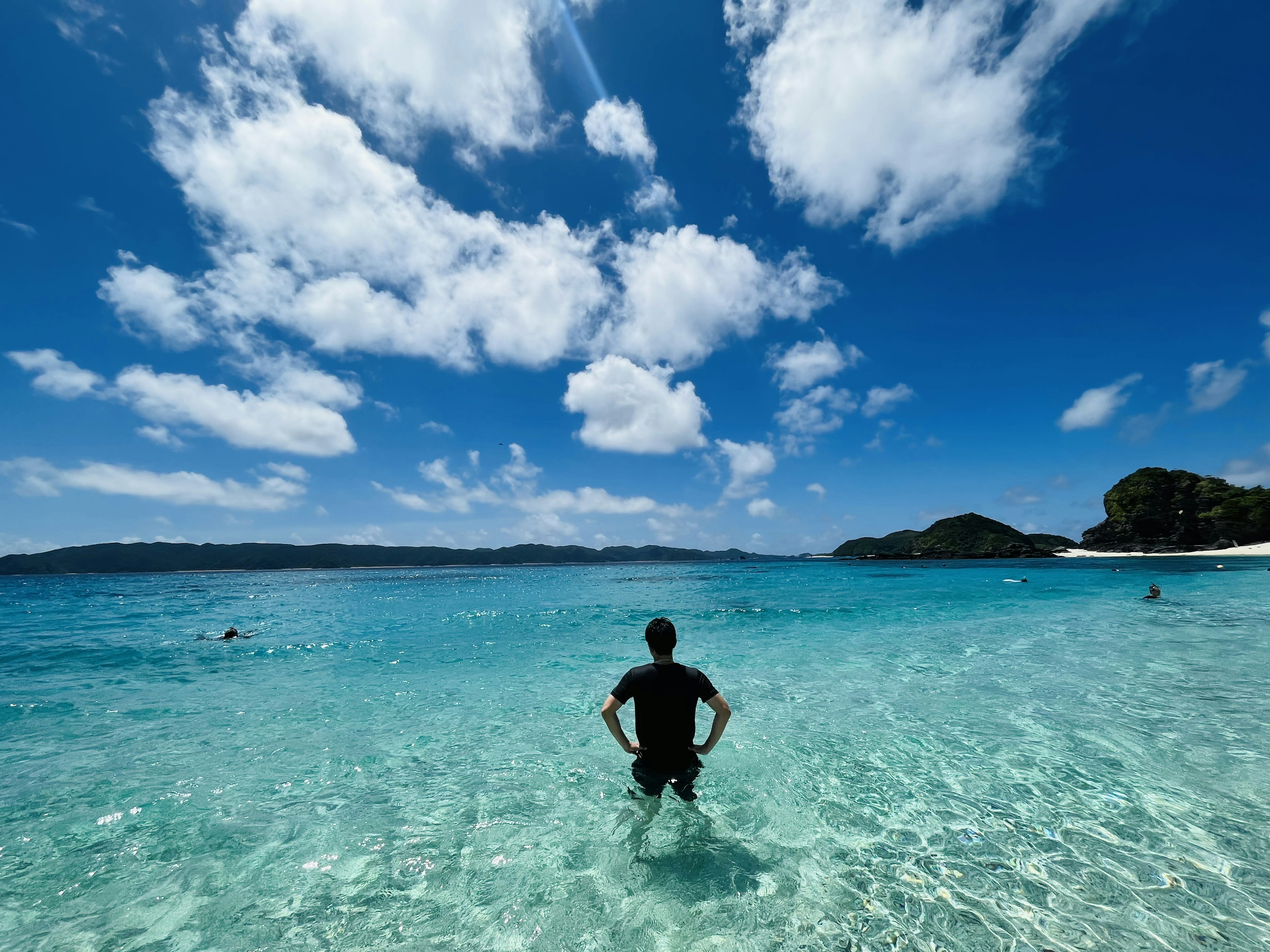 Person steht im klaren Wasser unter einem hellen Himmel