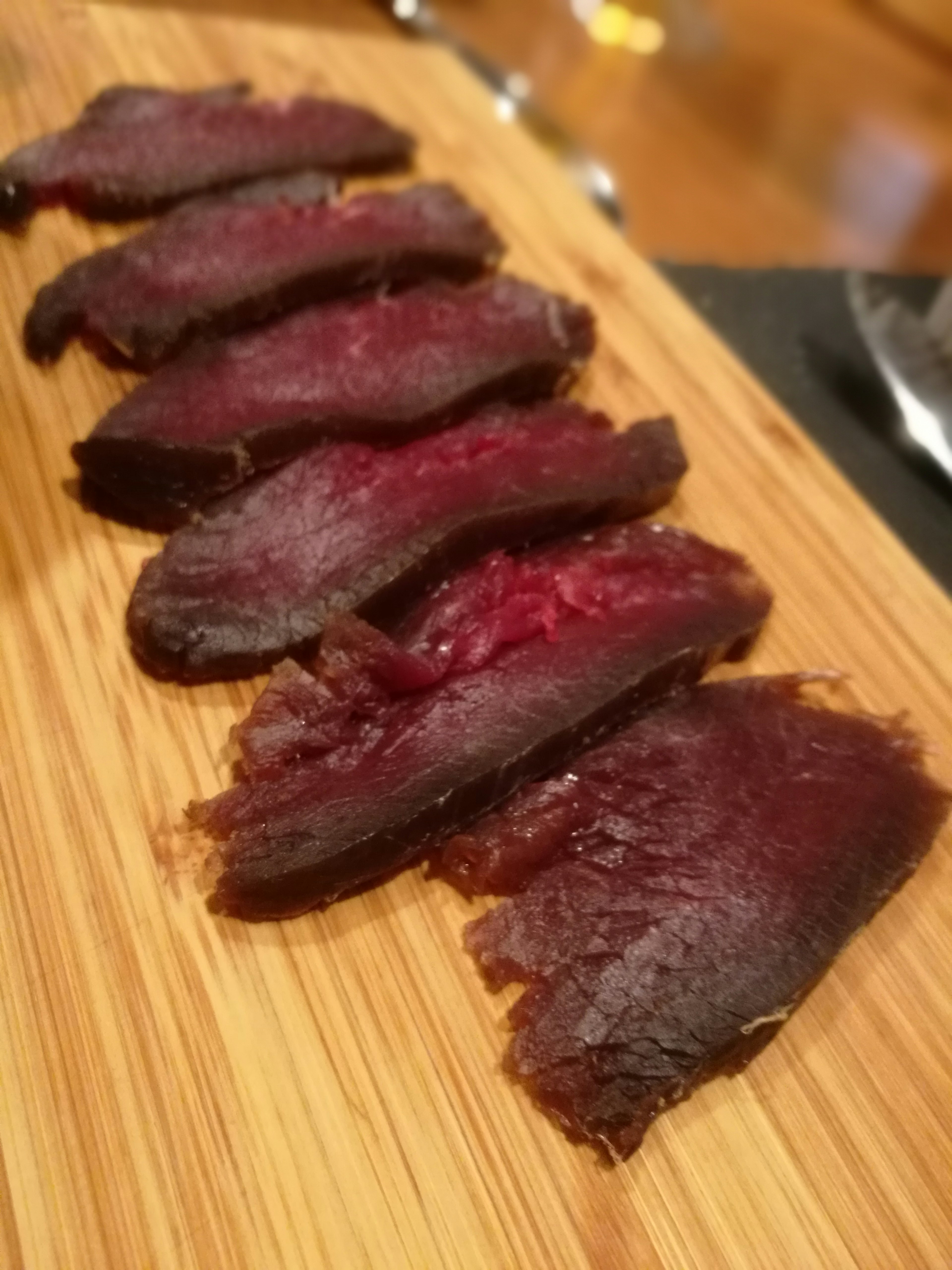 Sliced dried meat arranged on a wooden board