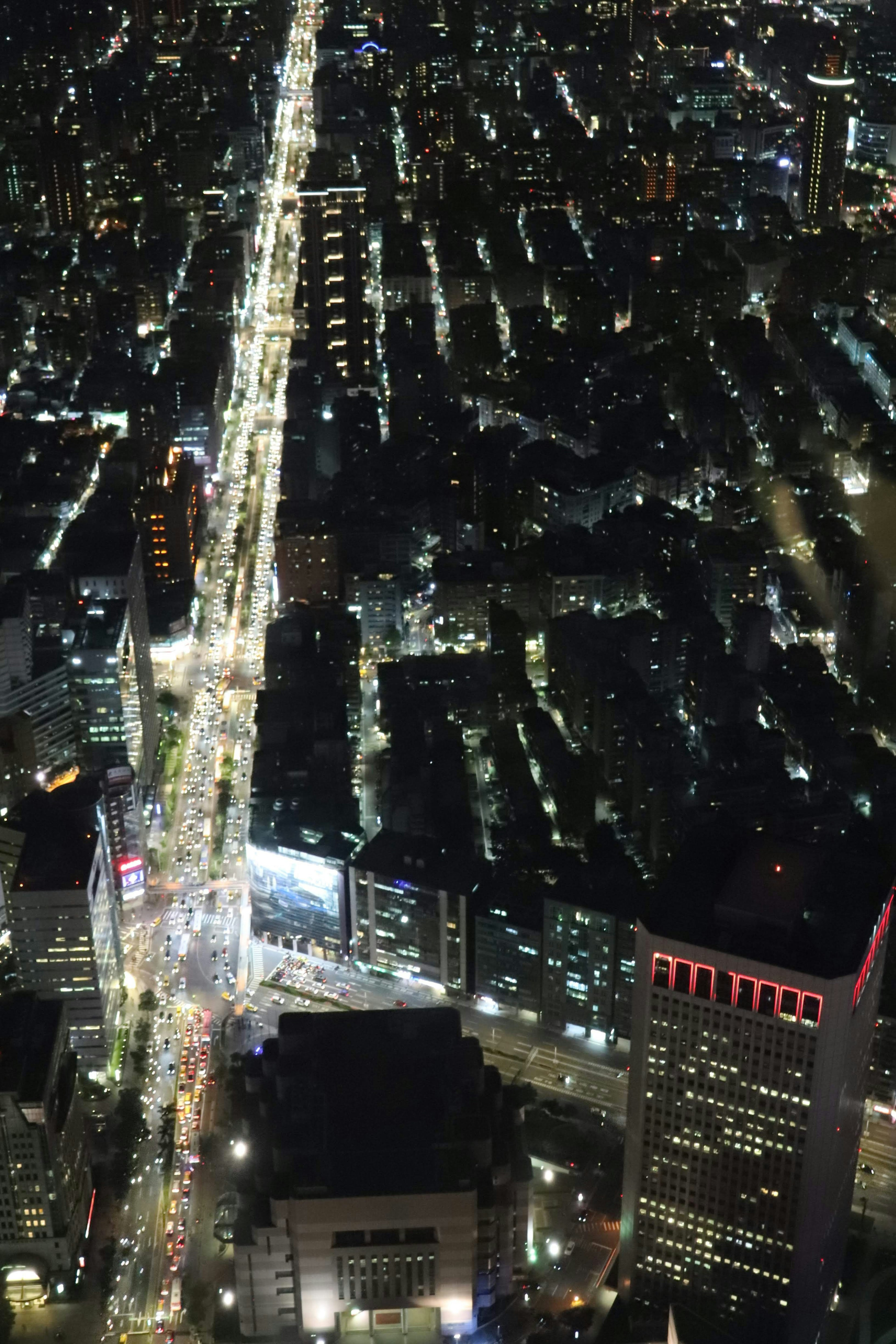 Aerial view of a city at night with bright lights illuminating the streets