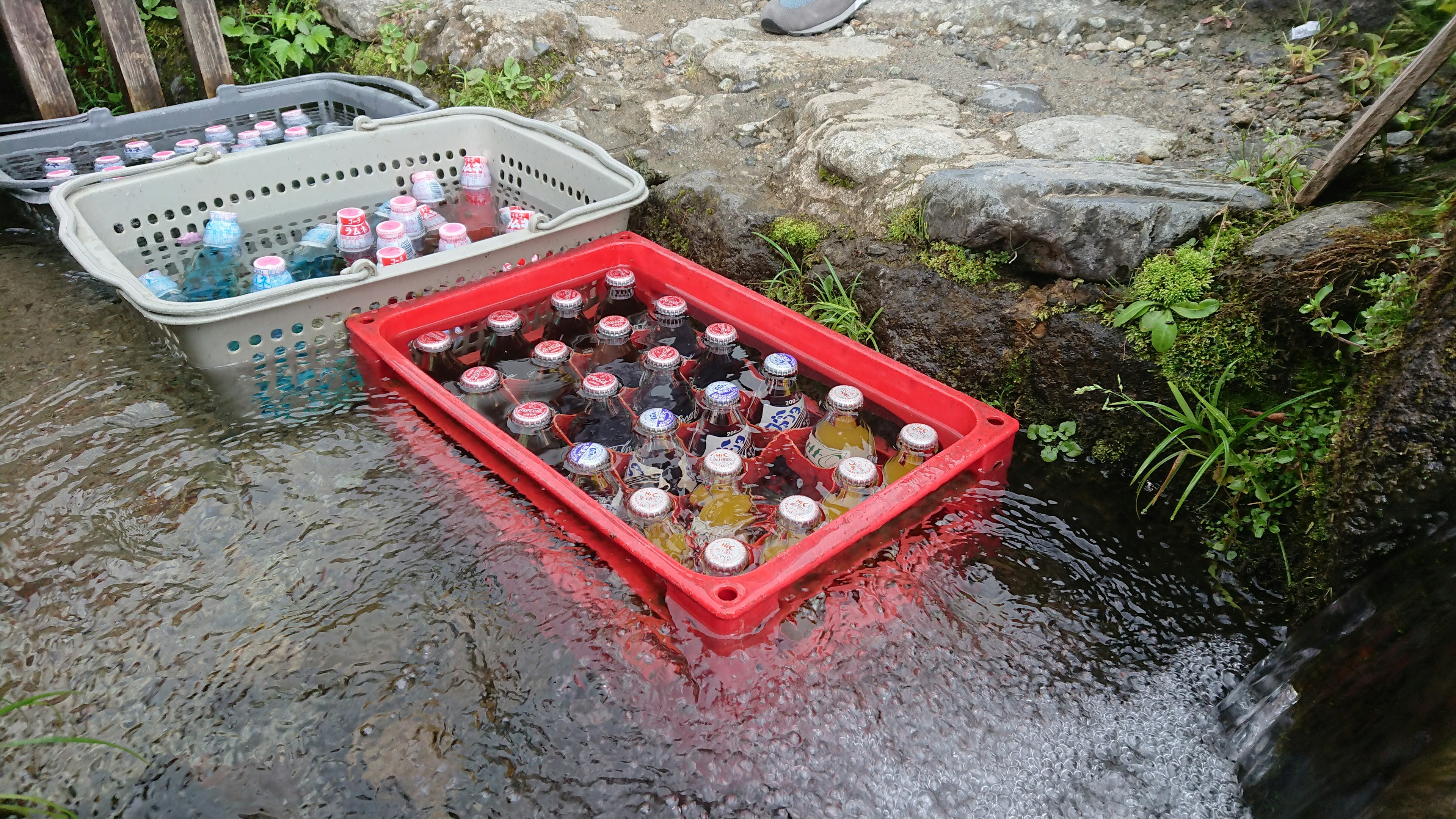 Rote Schale mit Getränkedosen, die im Wasser schwimmen, neben einem Korb