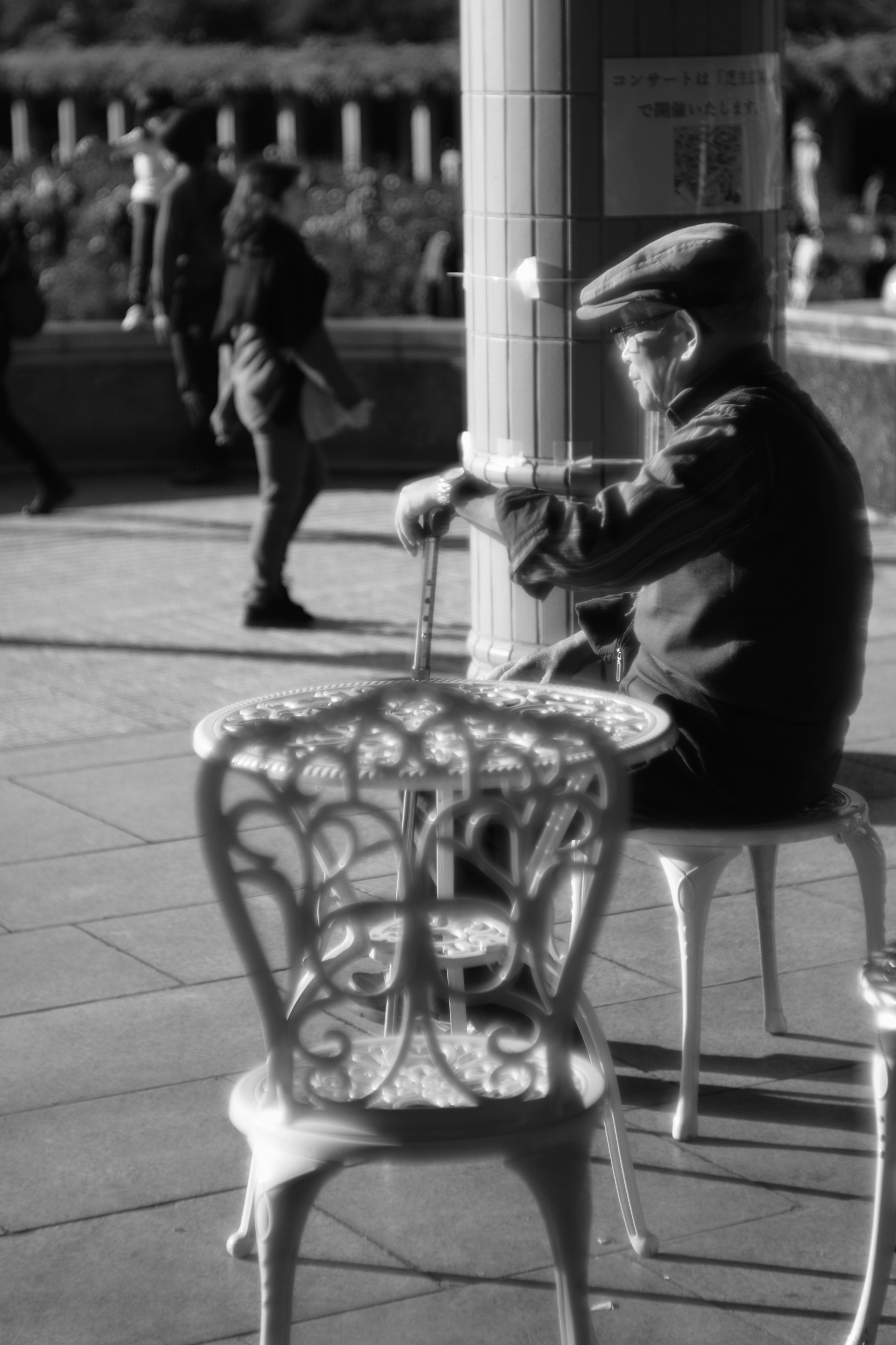 公園のベンチに座っている老人がフルートを演奏しているモノクロの写真