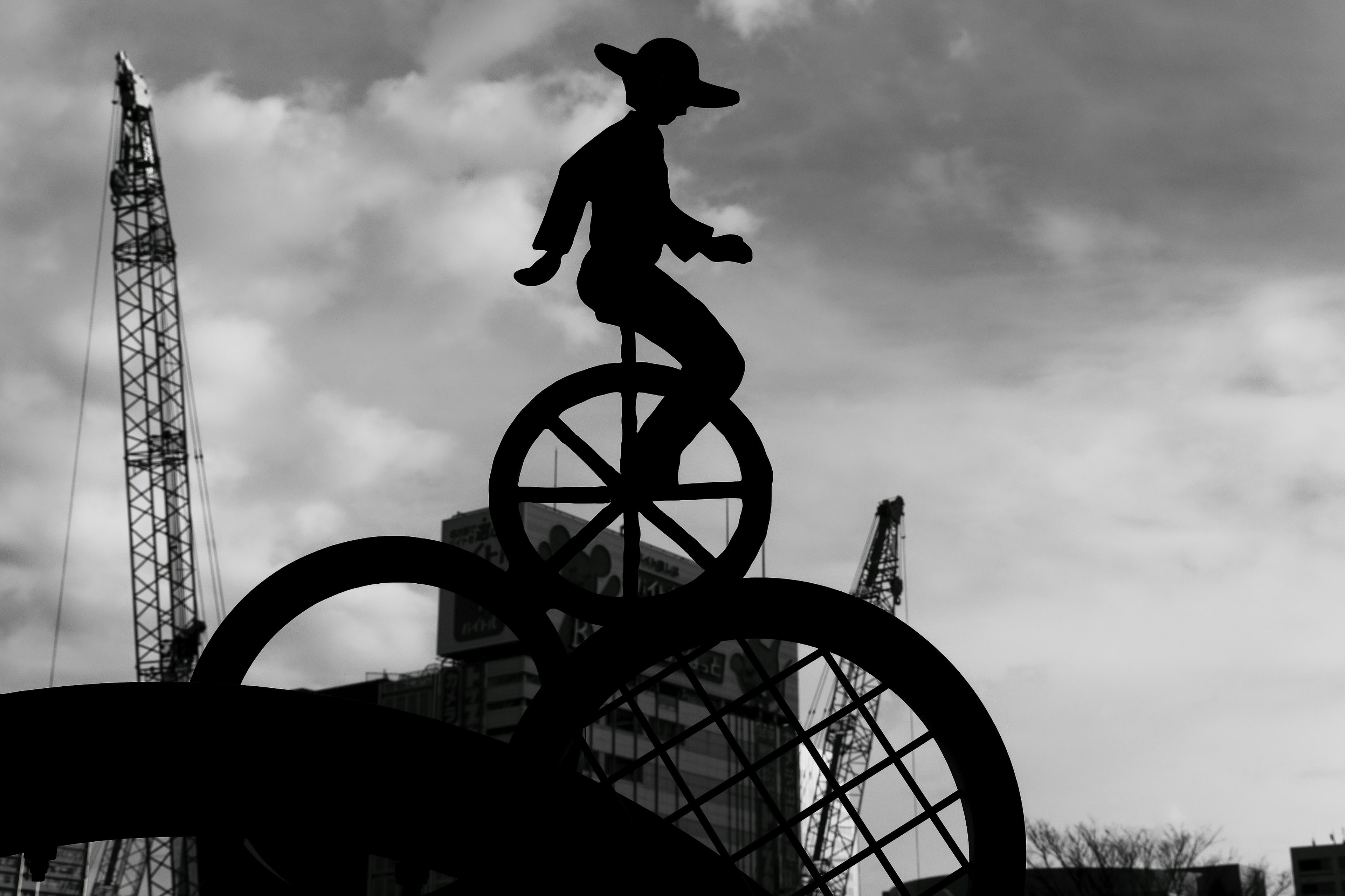 Silhouette of a person balancing on bicycle wheels against a monochrome sky