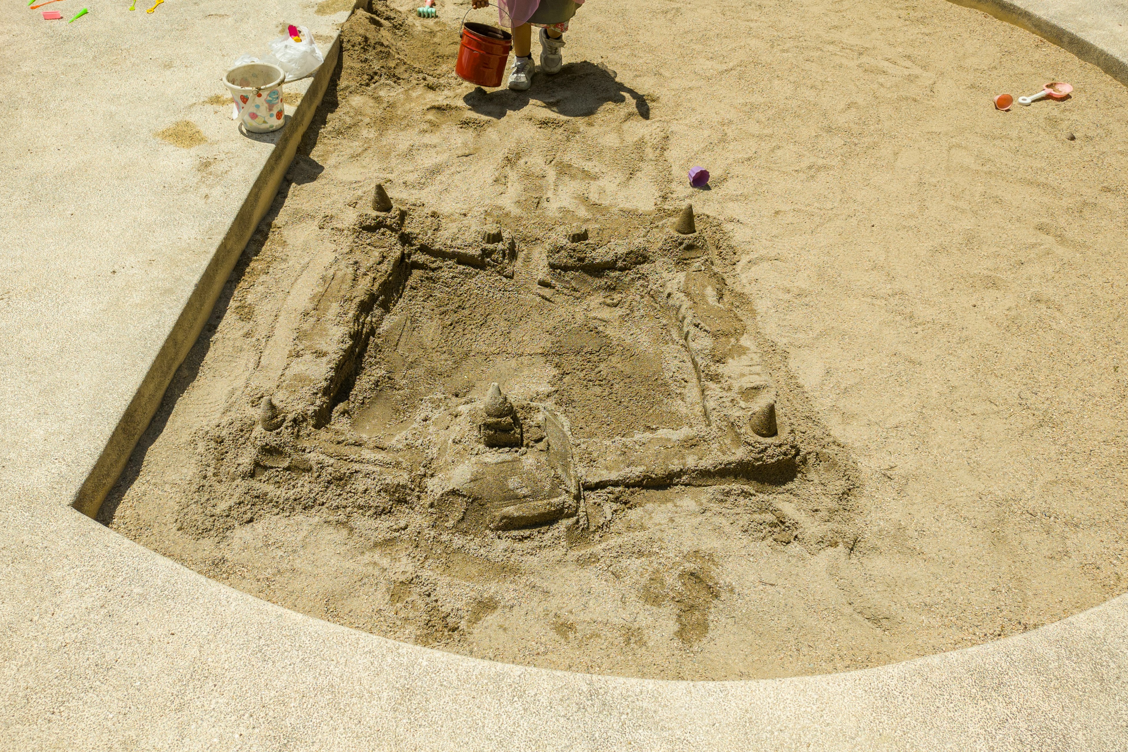 A sandcastle structure in a sandpit with various shapes and towers