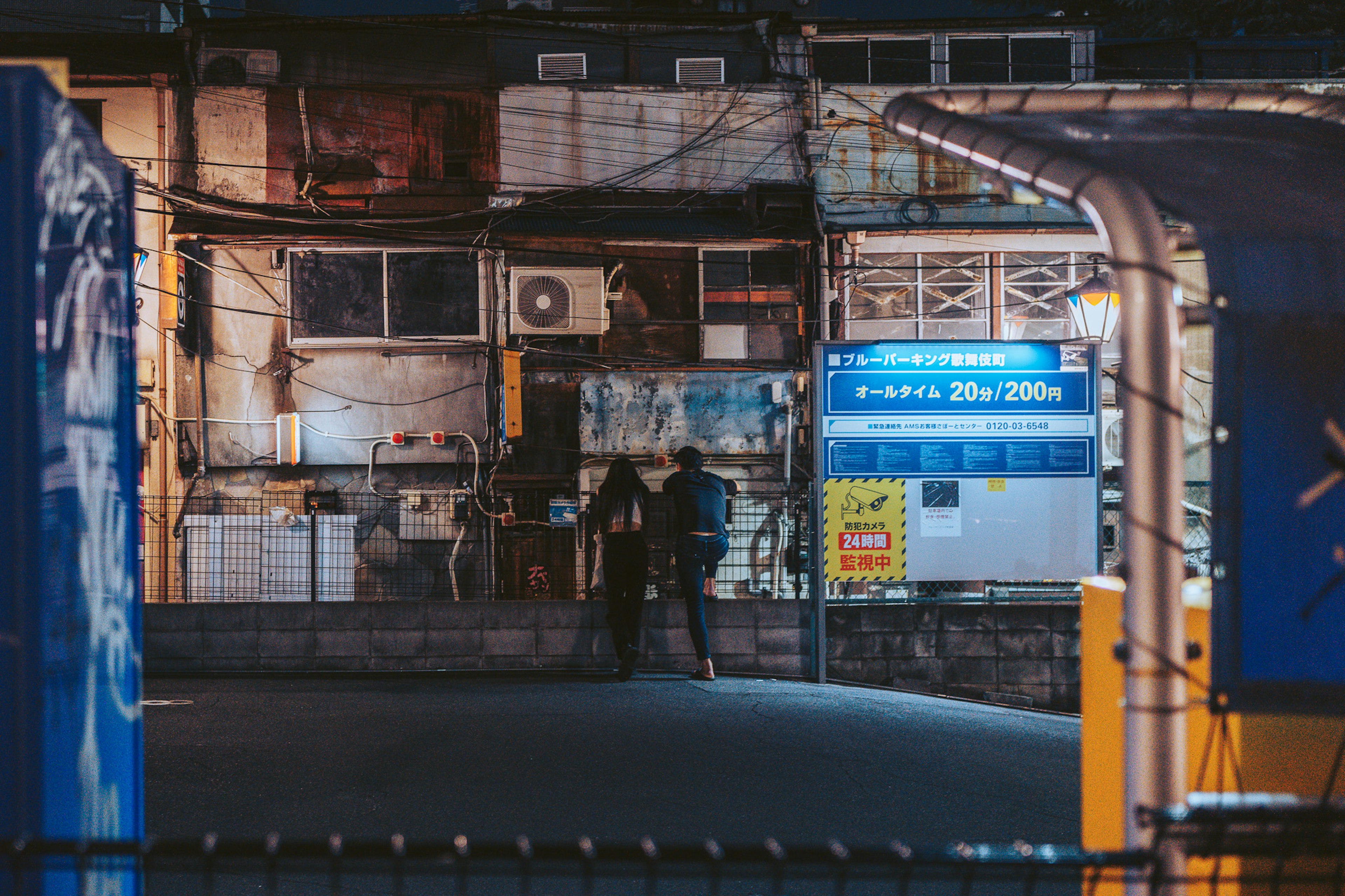 People standing in front of an old building at night with a blue sign