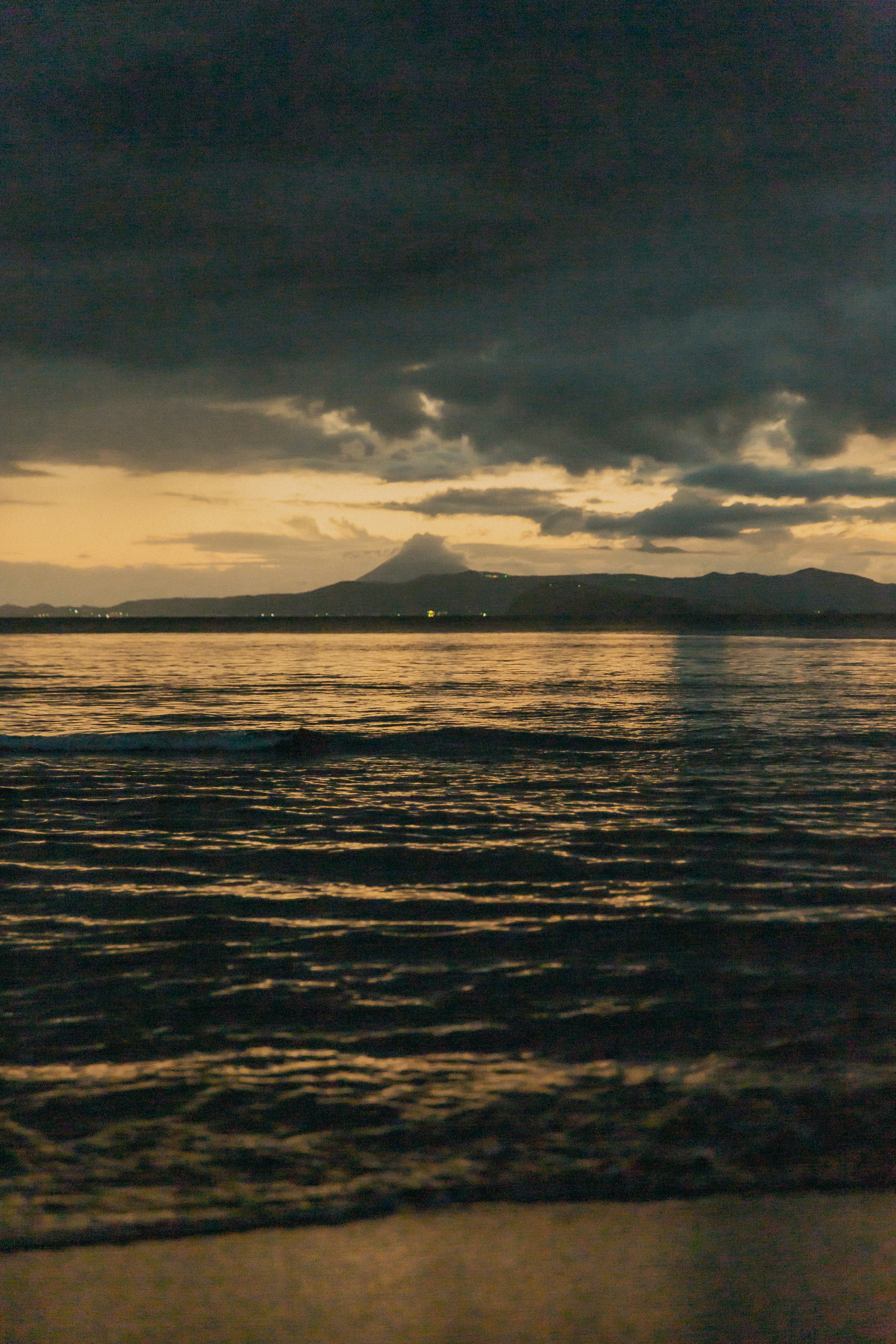 Paysage maritime nuageux sombre avec une montagne lointaine et de l'eau scintillante