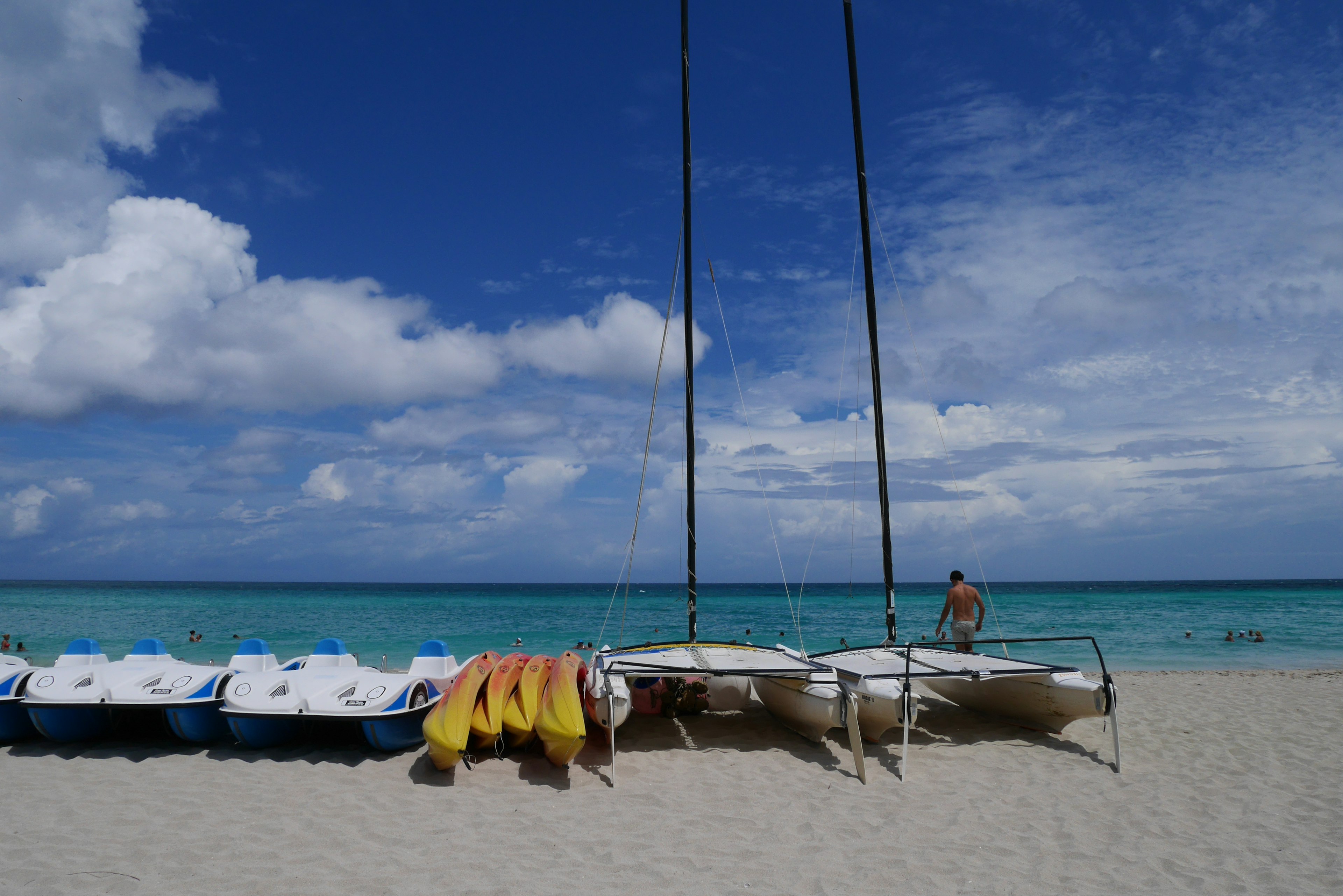 Kayak allineati sulla spiaggia con un albero maestro e cielo blu