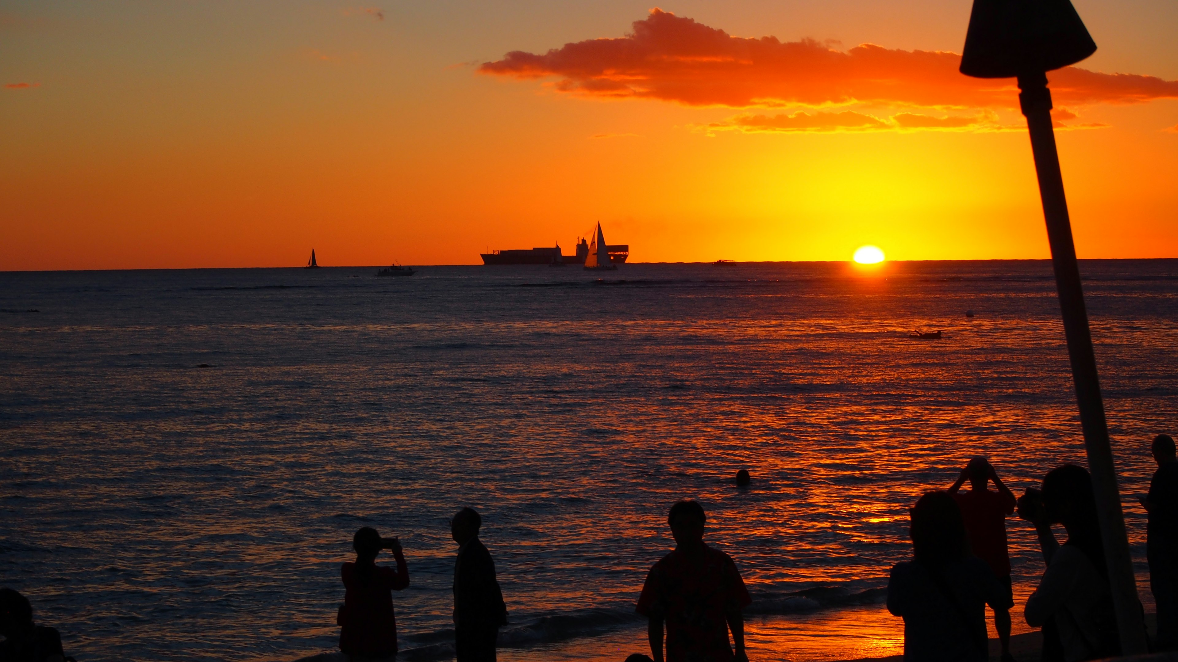 Escena de playa con atardecer y siluetas de personas