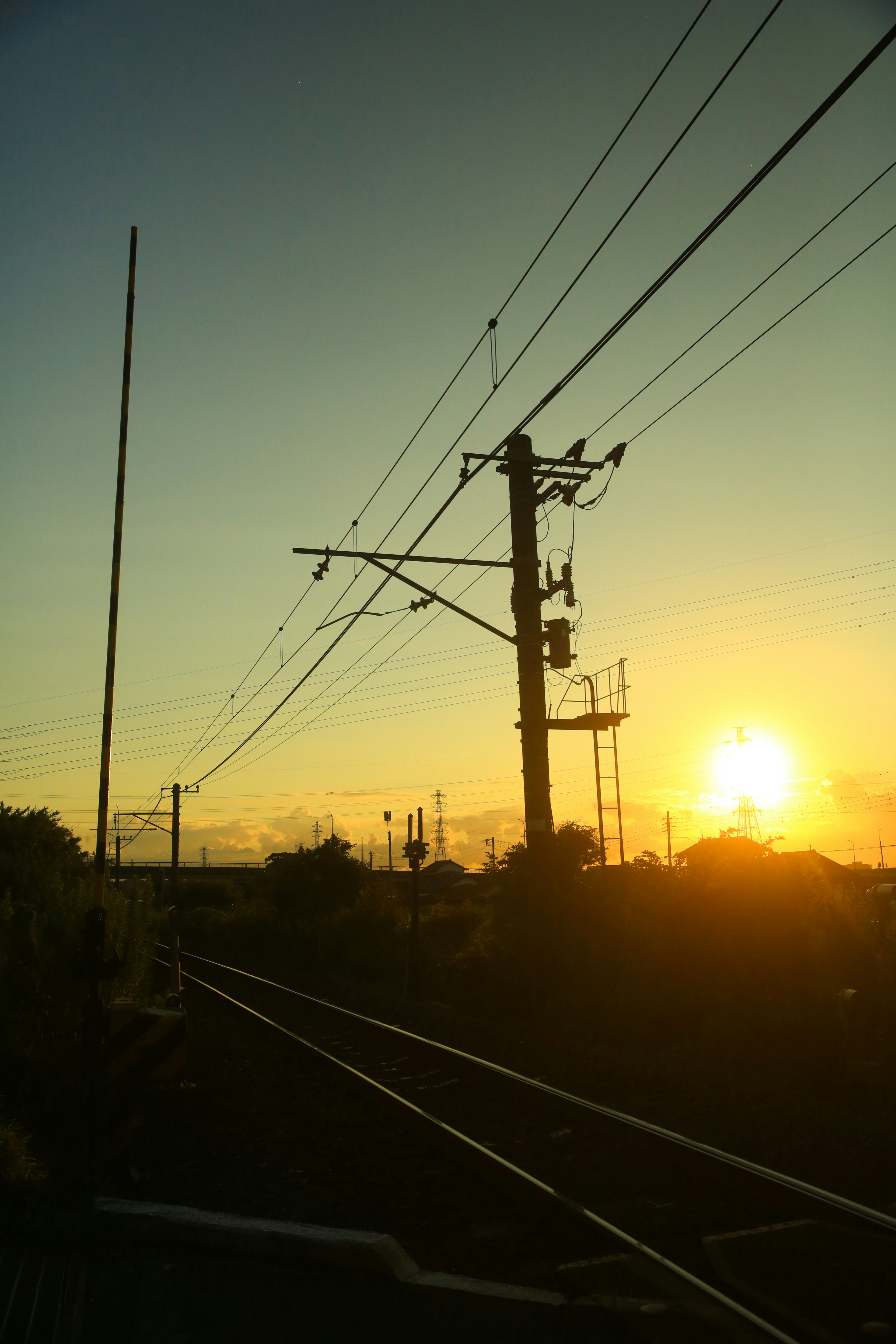 Silhouette di binari ferroviari e pali elettrici al tramonto