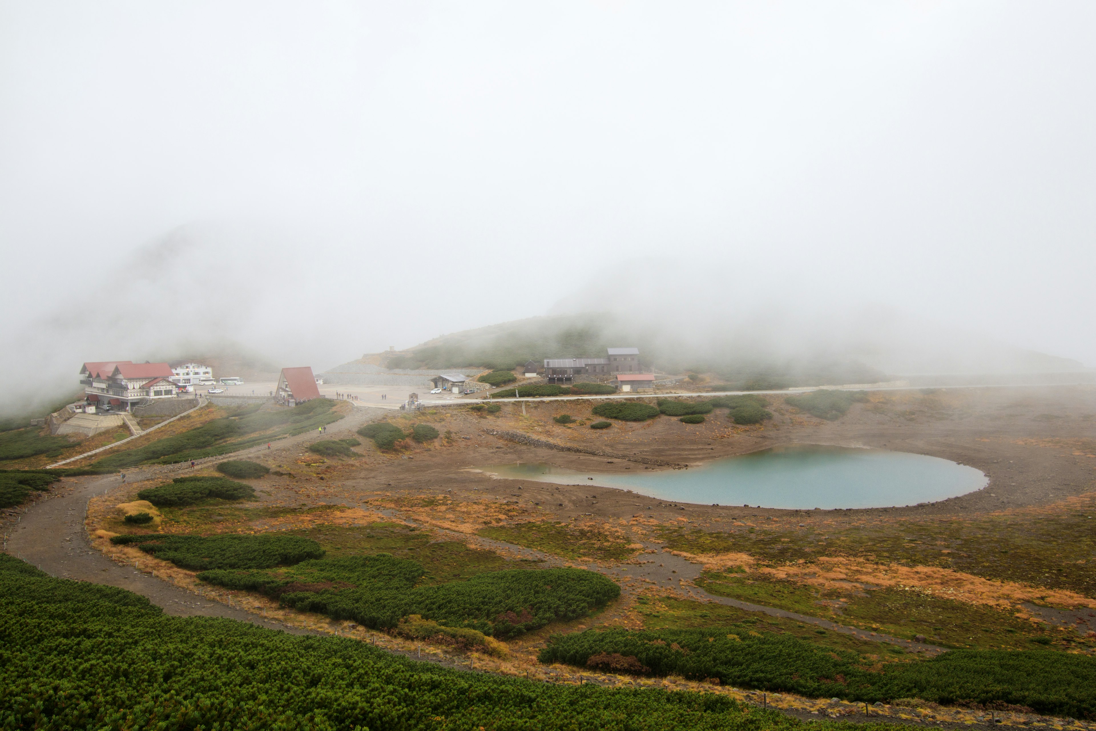 Paisaje montañoso cubierto de niebla con un pequeño estanque