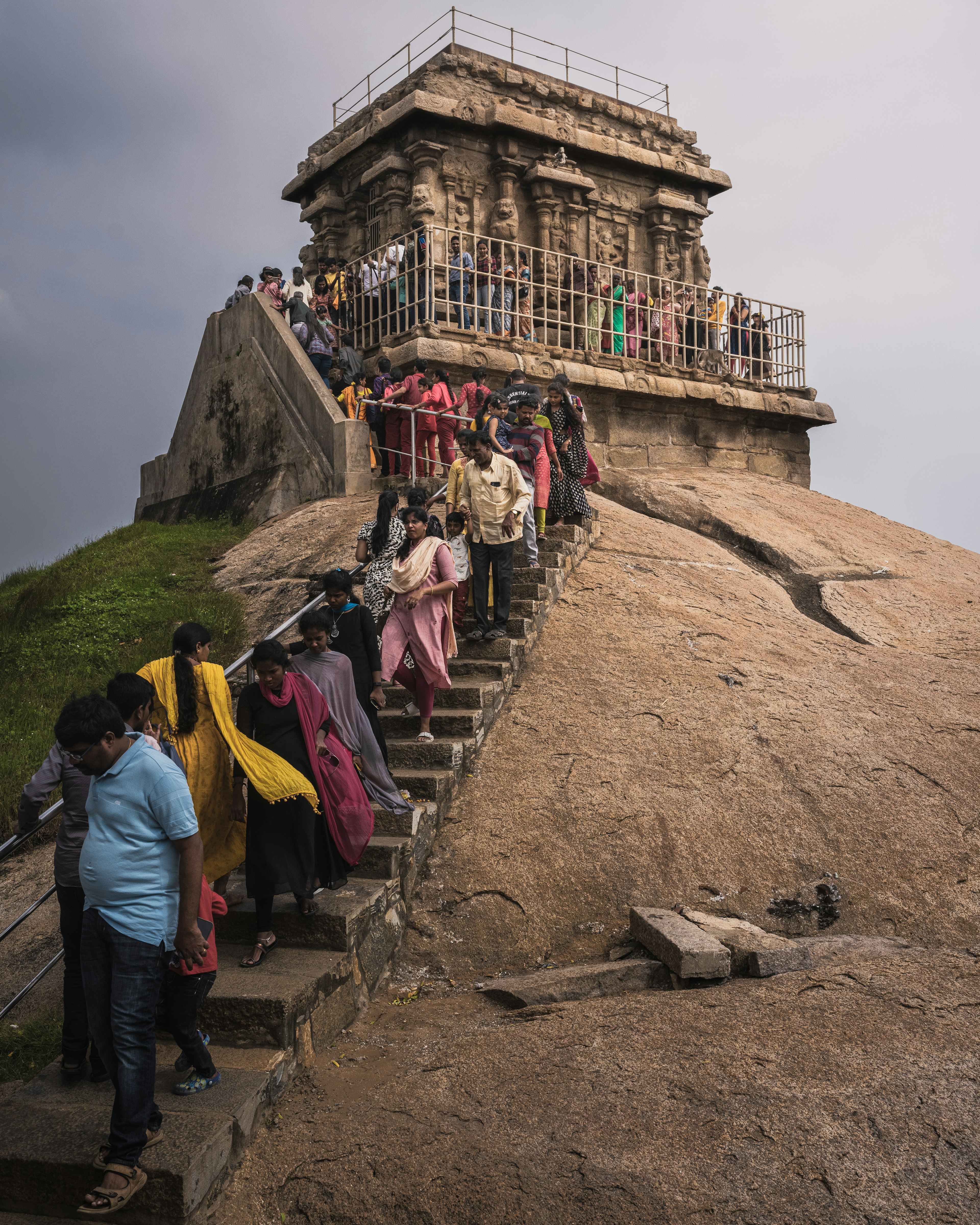 Eine Gruppe von Menschen, die steinerne Stufen zu einem Tempel auf einem felsigen Hügel hinaufsteigt