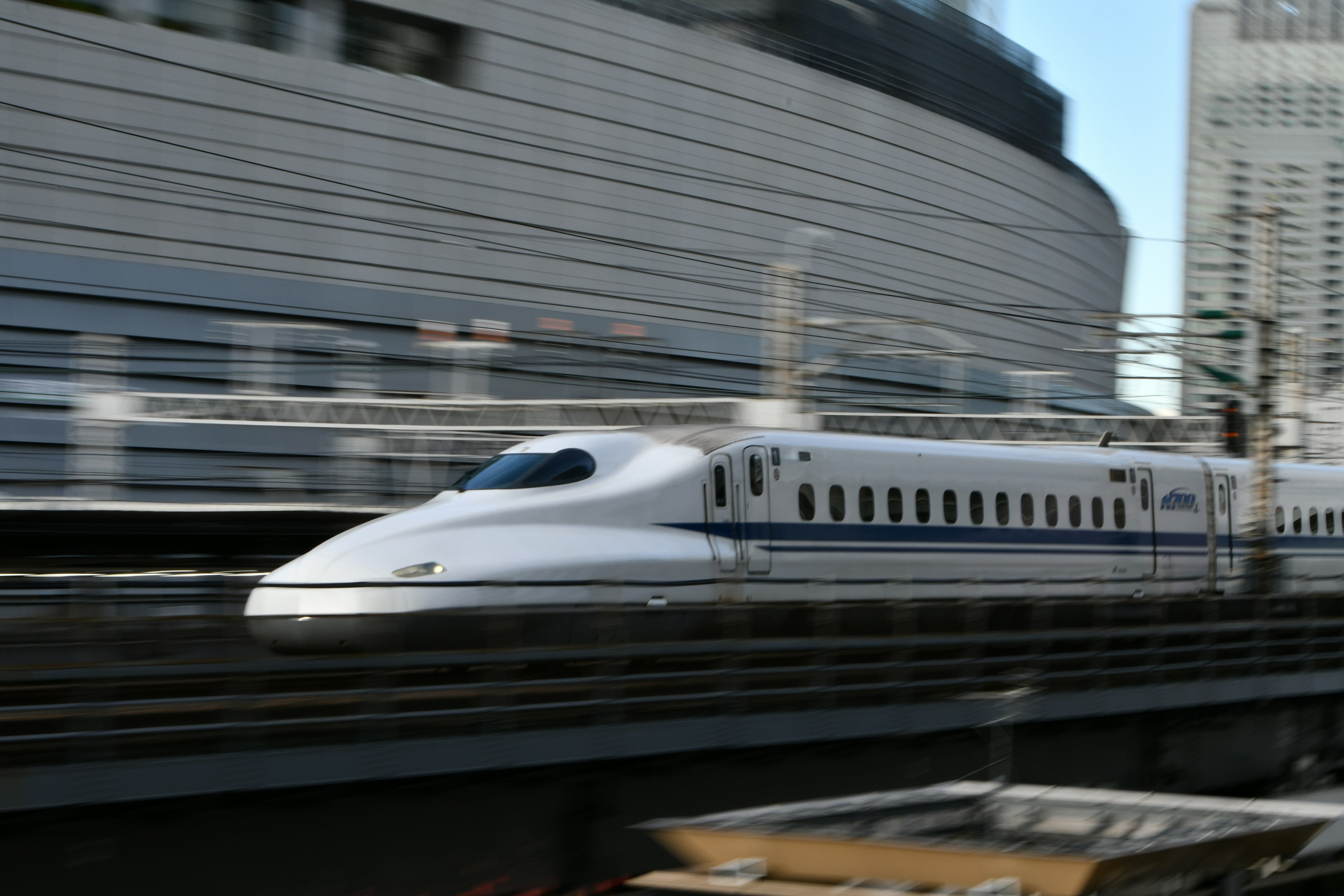 Shinkansen speeding past with urban buildings in the background