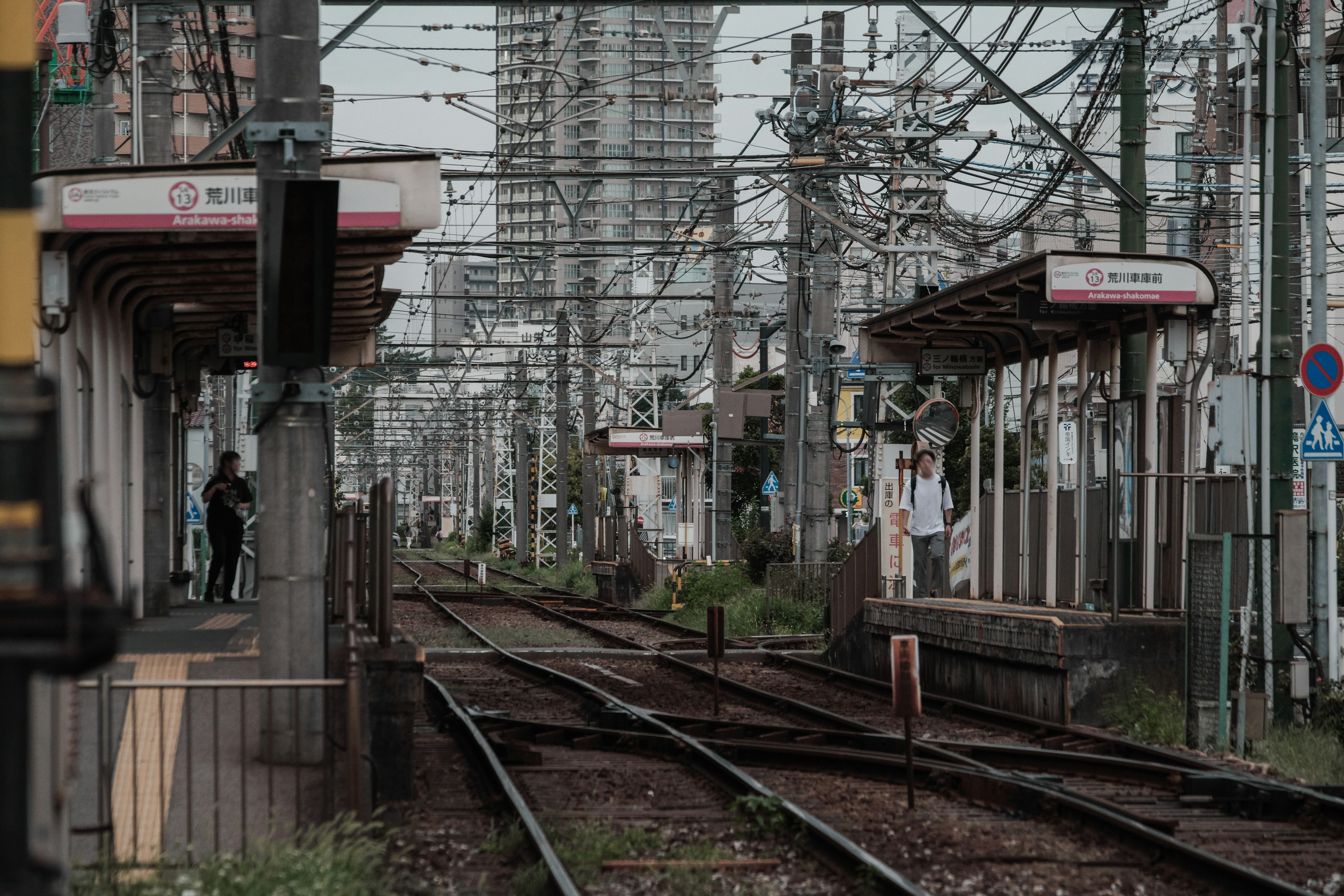 Pemandangan stasiun kereta dengan rel dan orang-orang menunggu