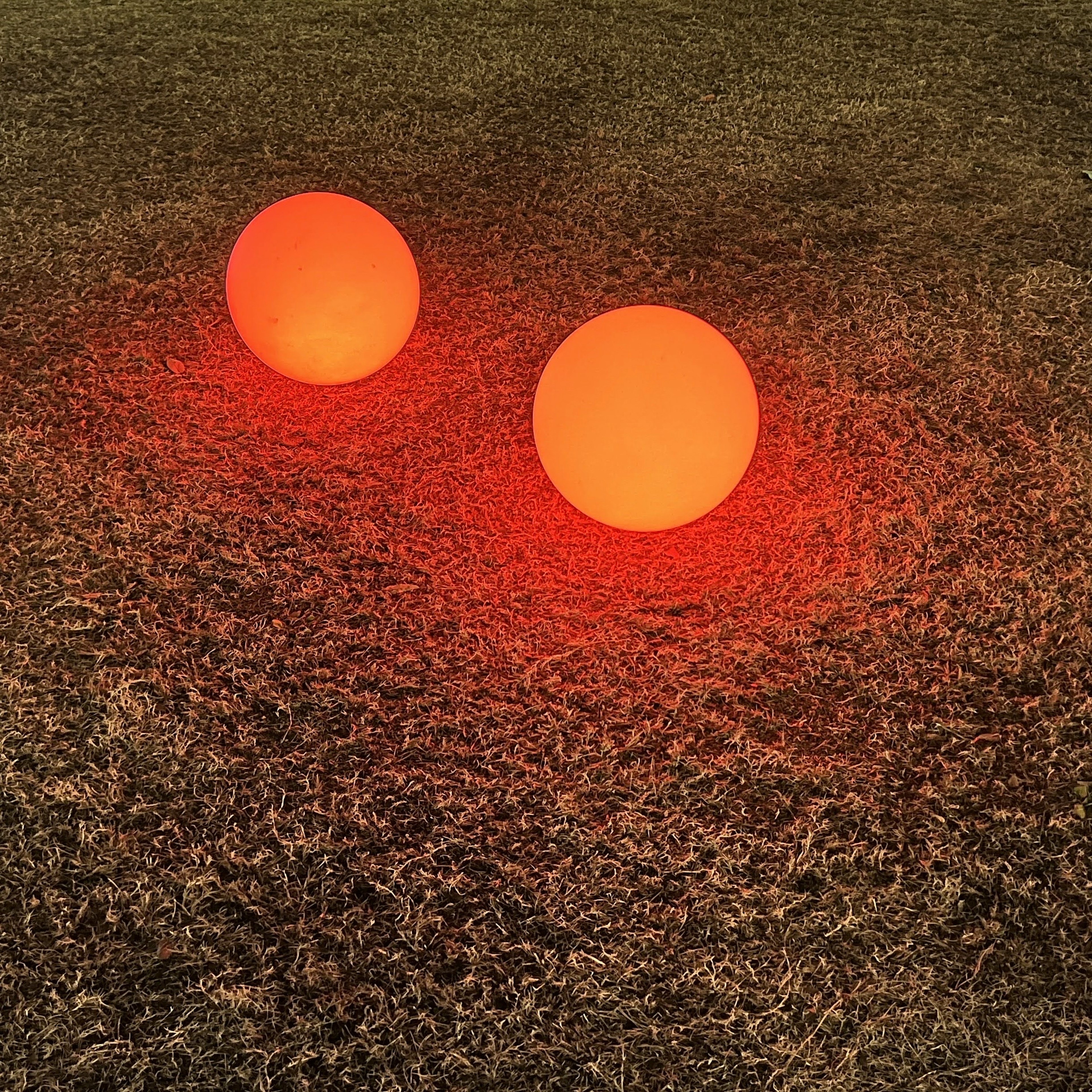 Two orange spheres placed on grassy ground