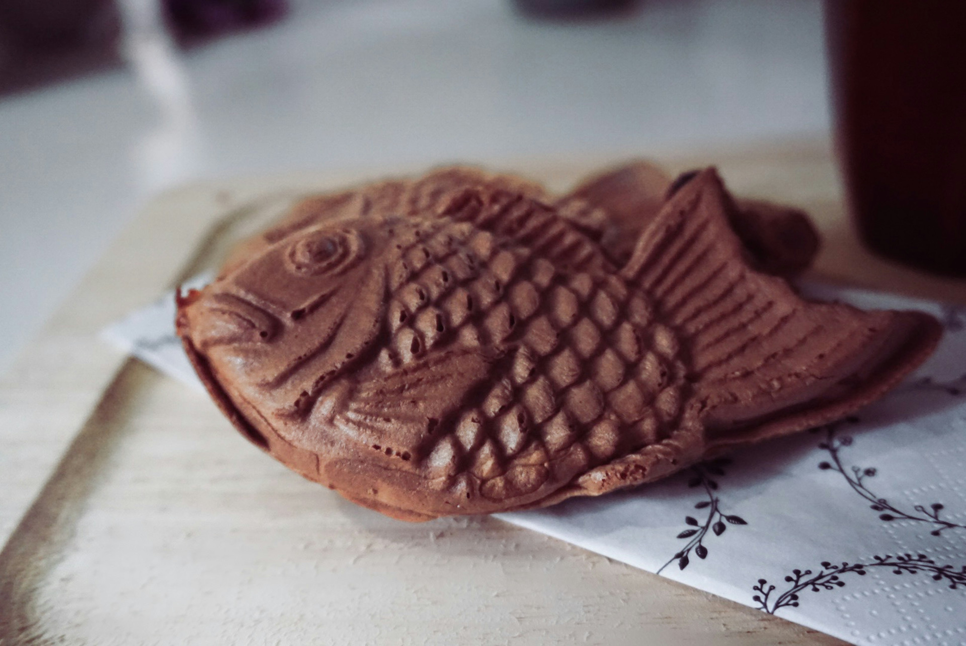 Une pâtisserie en forme de poisson reposant sur une assiette en bois