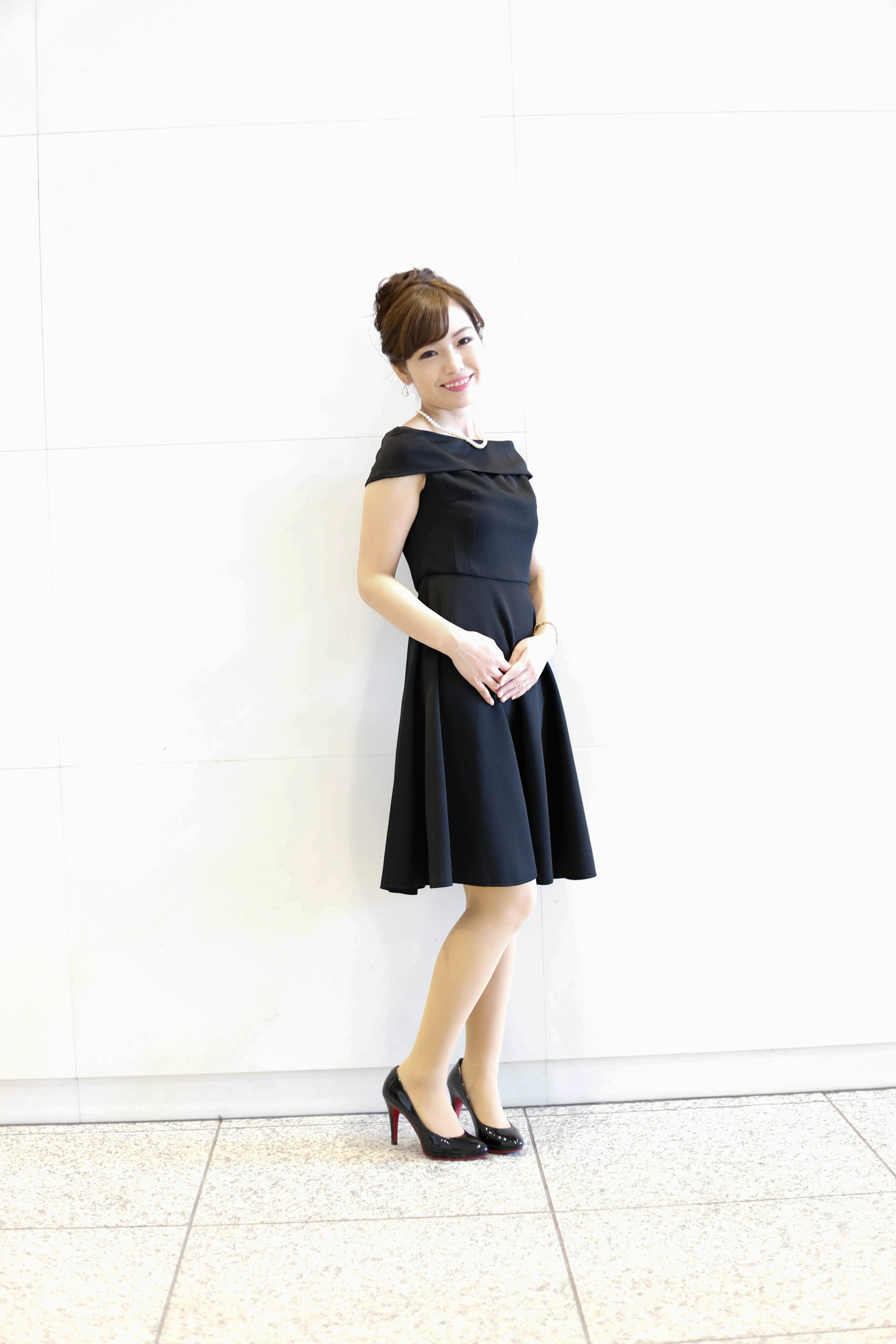 A woman in a black dress standing against a white background