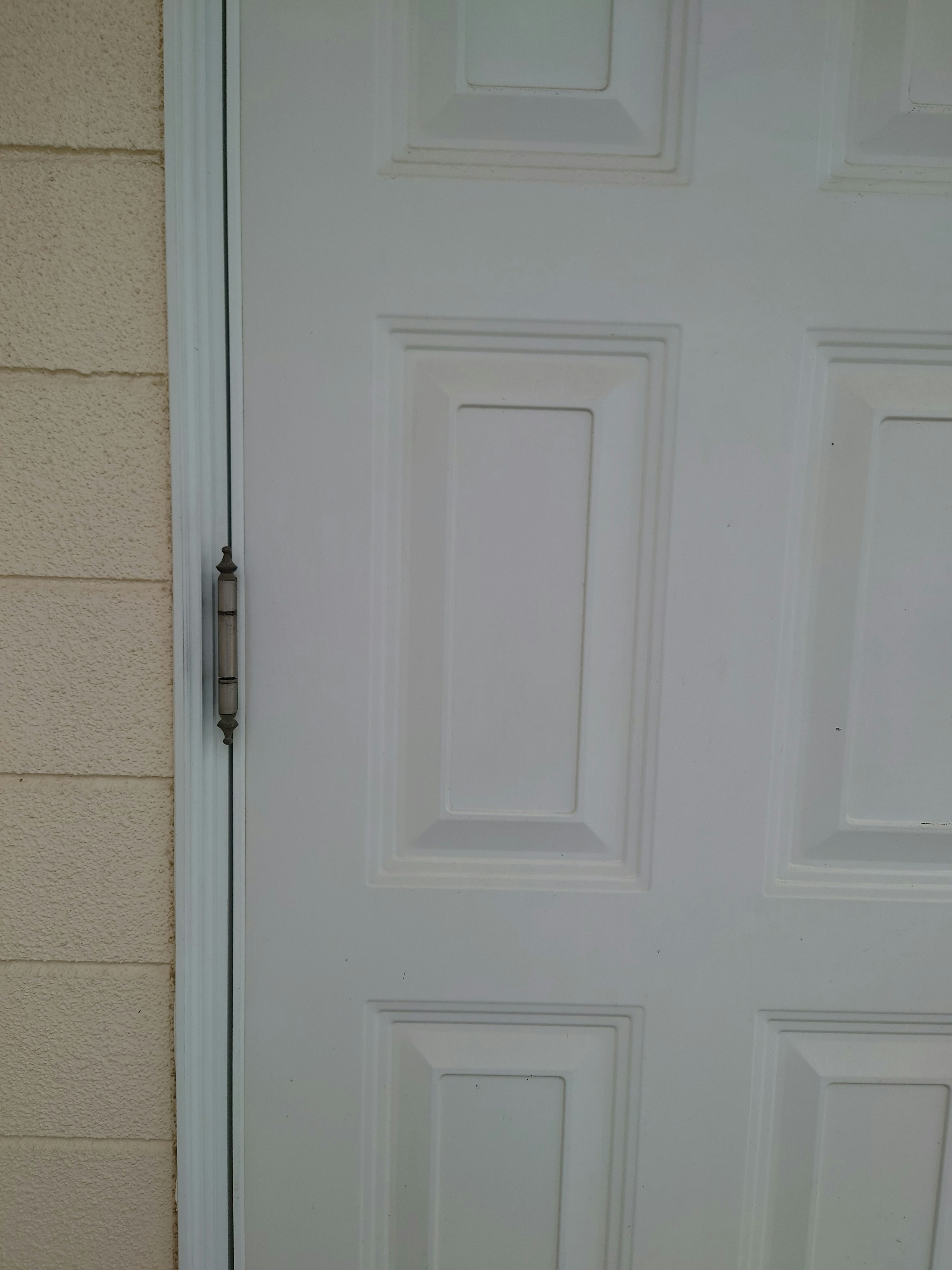 Close-up of a white door with a simple design featuring square panels adjacent to a cream-colored wall