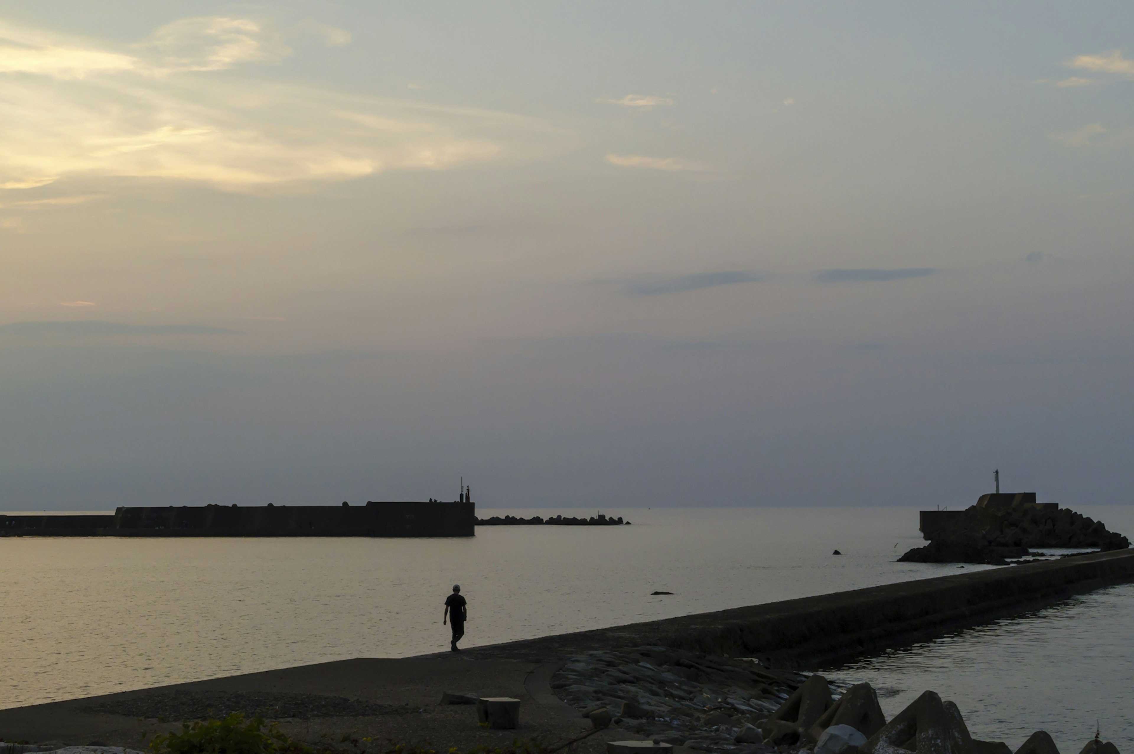 Un paysage maritime tranquille au crépuscule avec une personne marchant le long du rivage