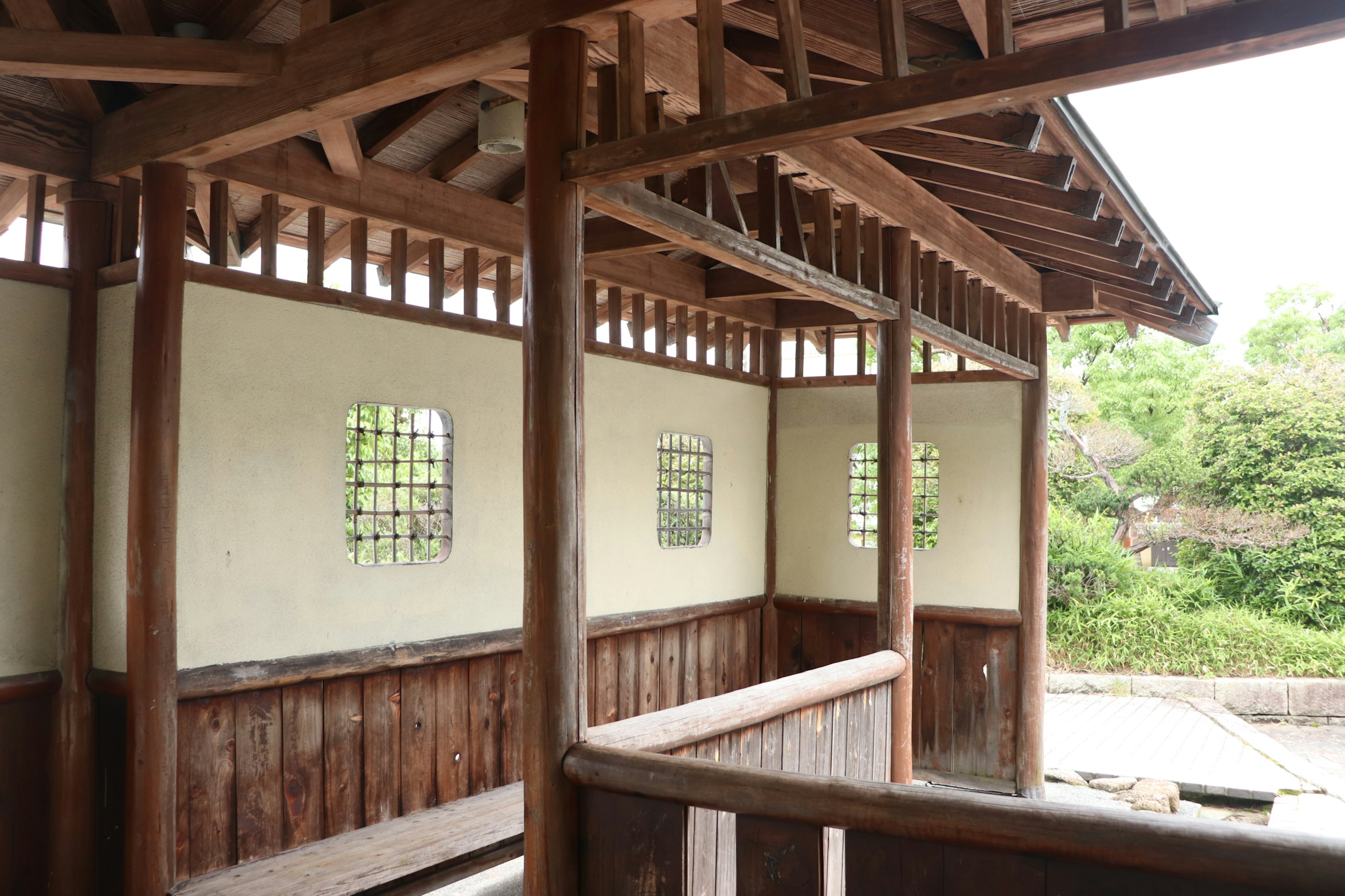 Interior de una casa japonesa de madera con ventanas distintivas y naturaleza circundante visible