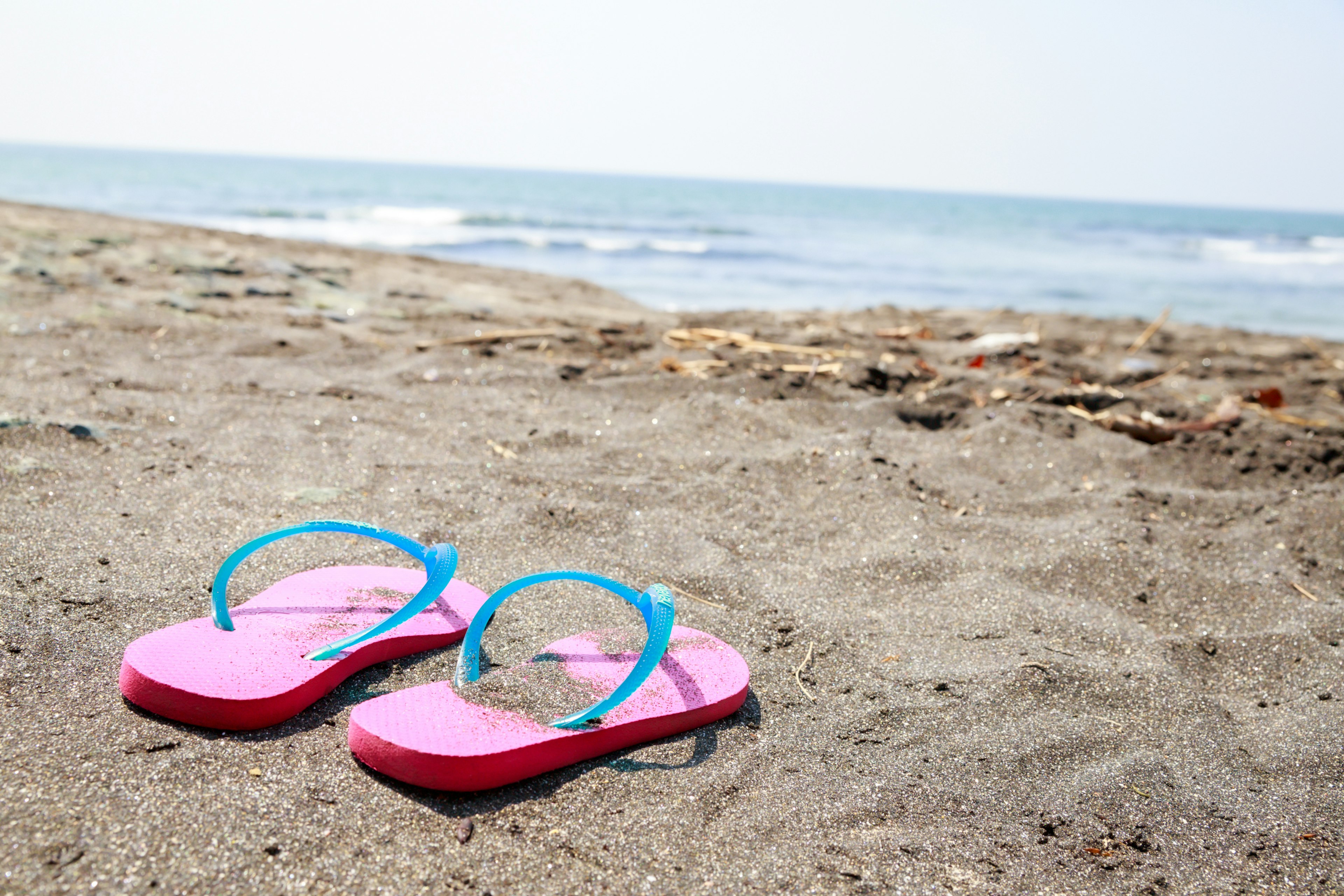 Pink flip-flops with blue straps on the beach