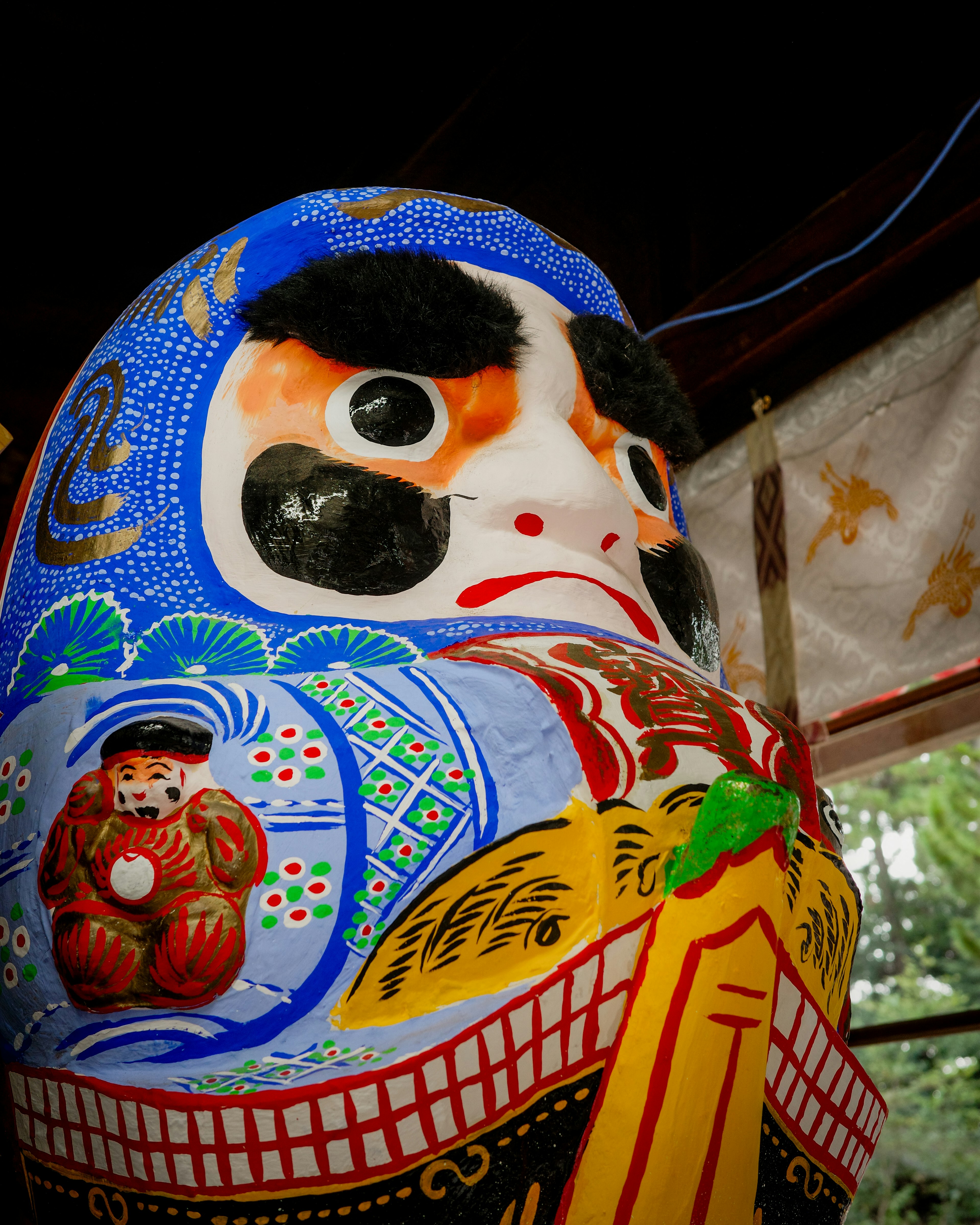 Daruma doll with intricate blue patterns and expressive face