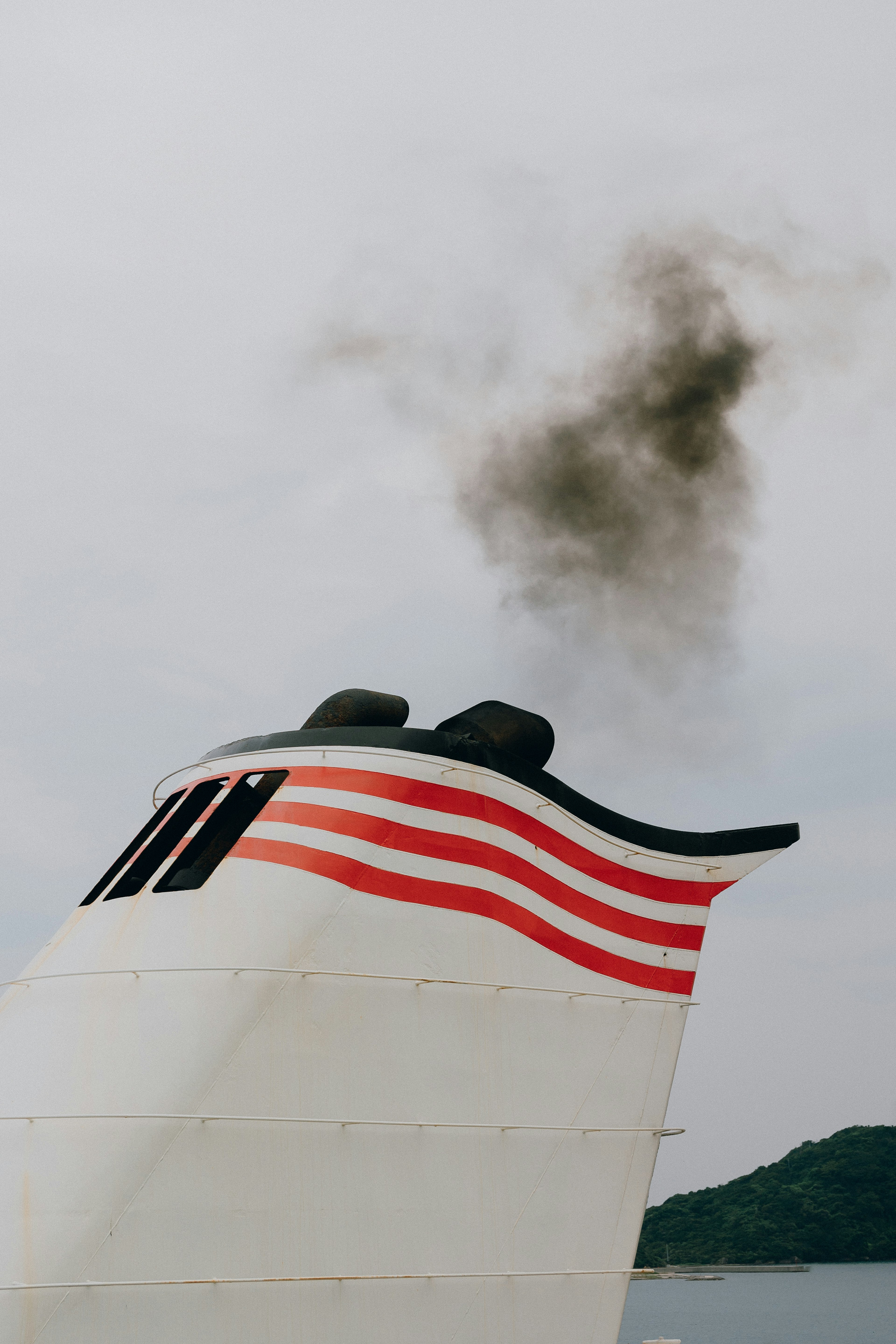 Smoke billowing from a ship's smokestack with red striped design