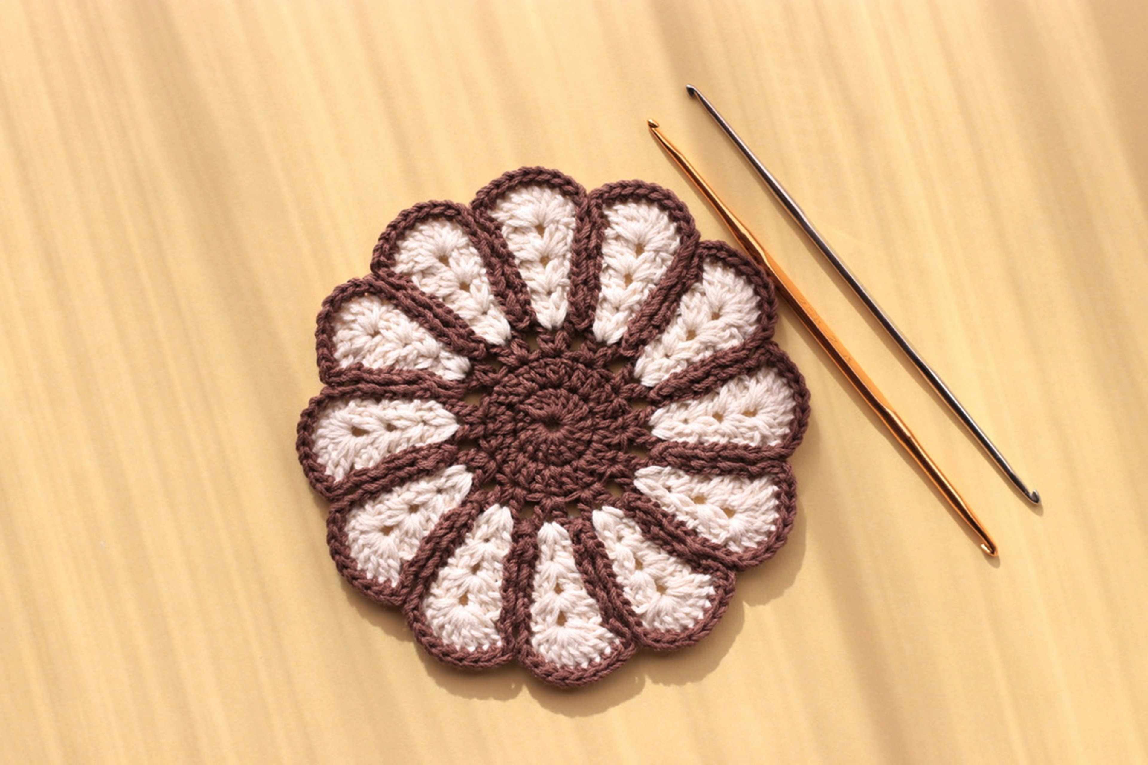 Dessous de verre en crochet en forme de fleur marron et blanc avec deux crochets à laine