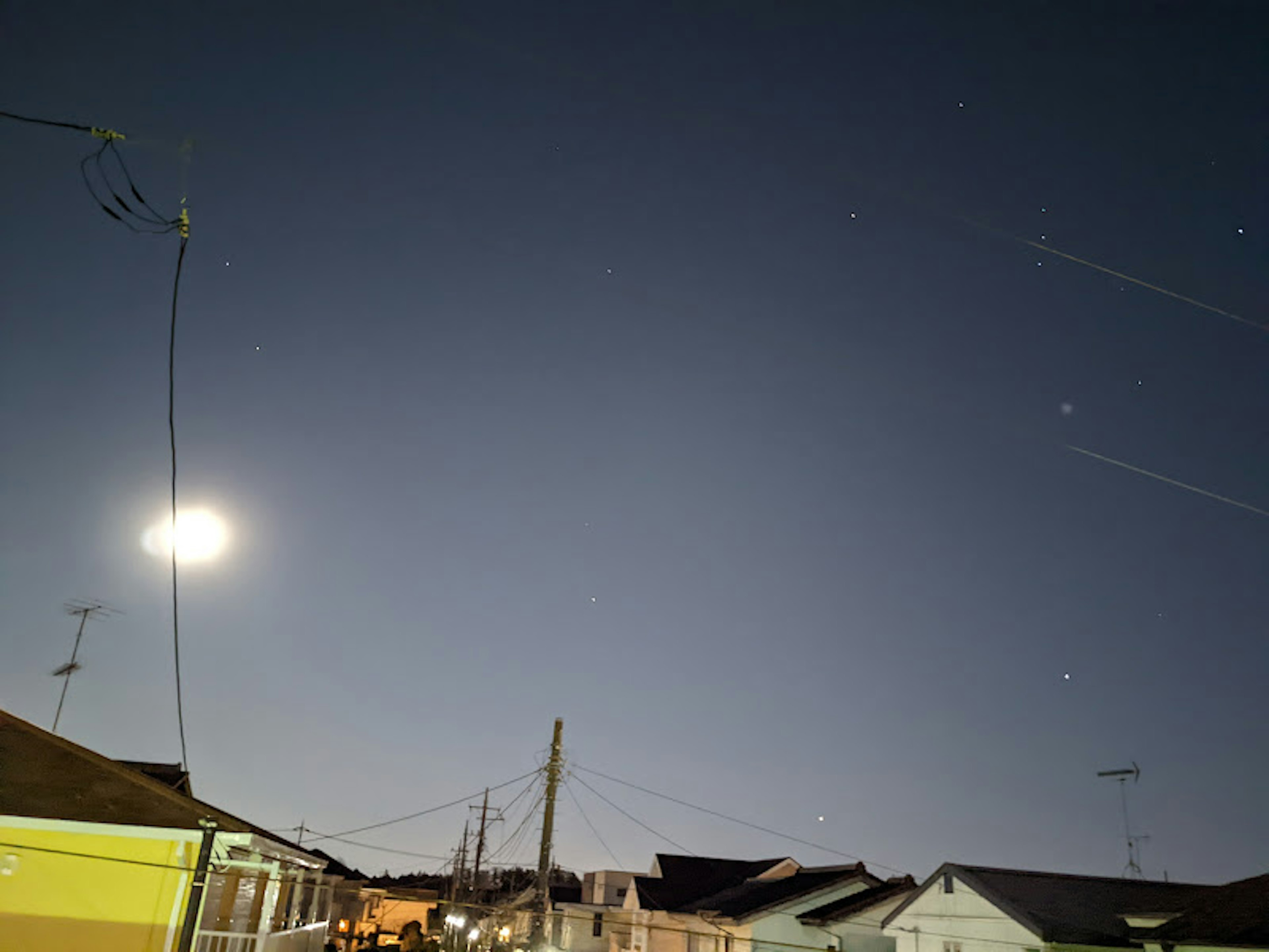 Night sky with moon and stars view residential area lights glowing