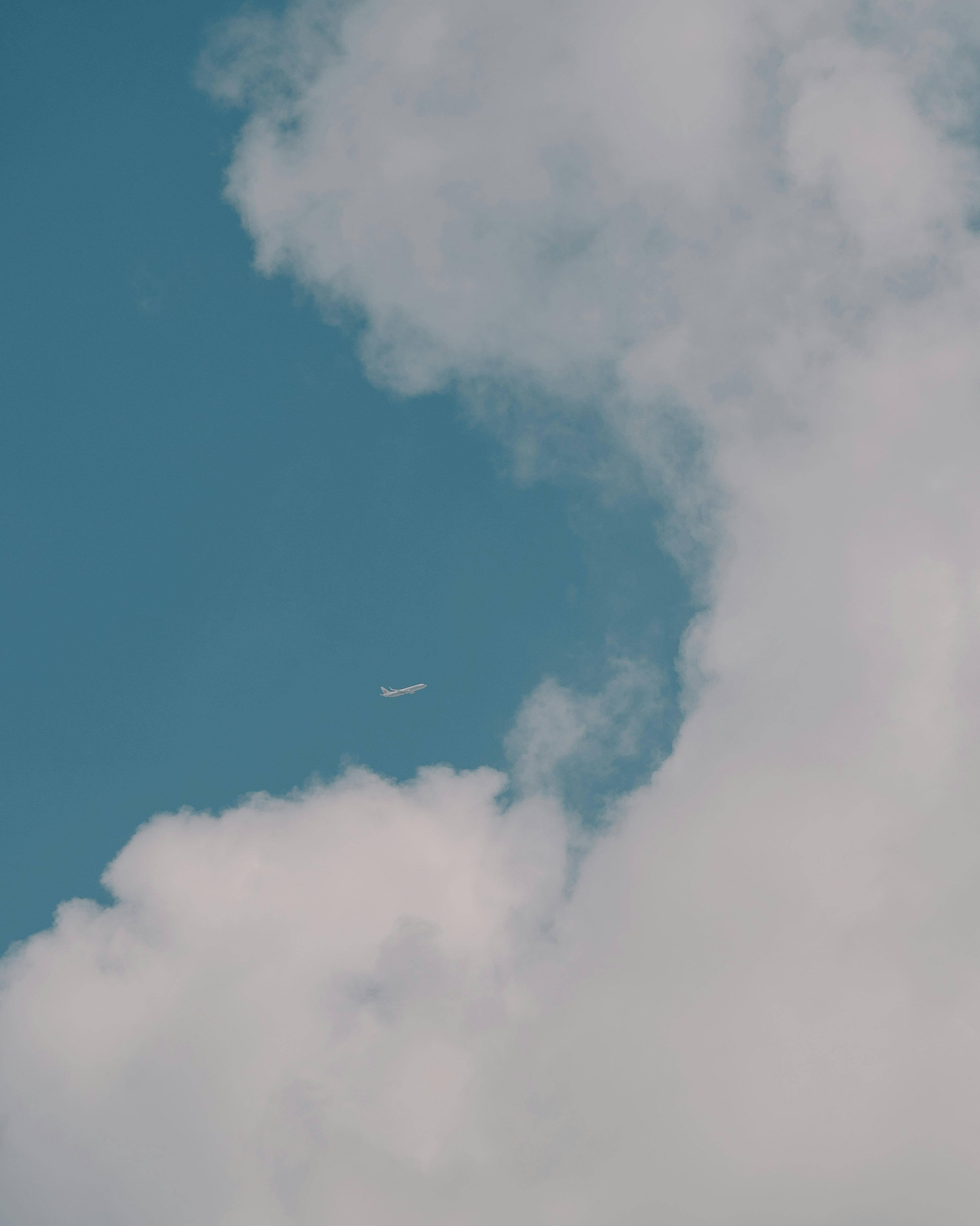 Weiße Wolken in einem blauen Himmel mit einem kleinen Flugzeug