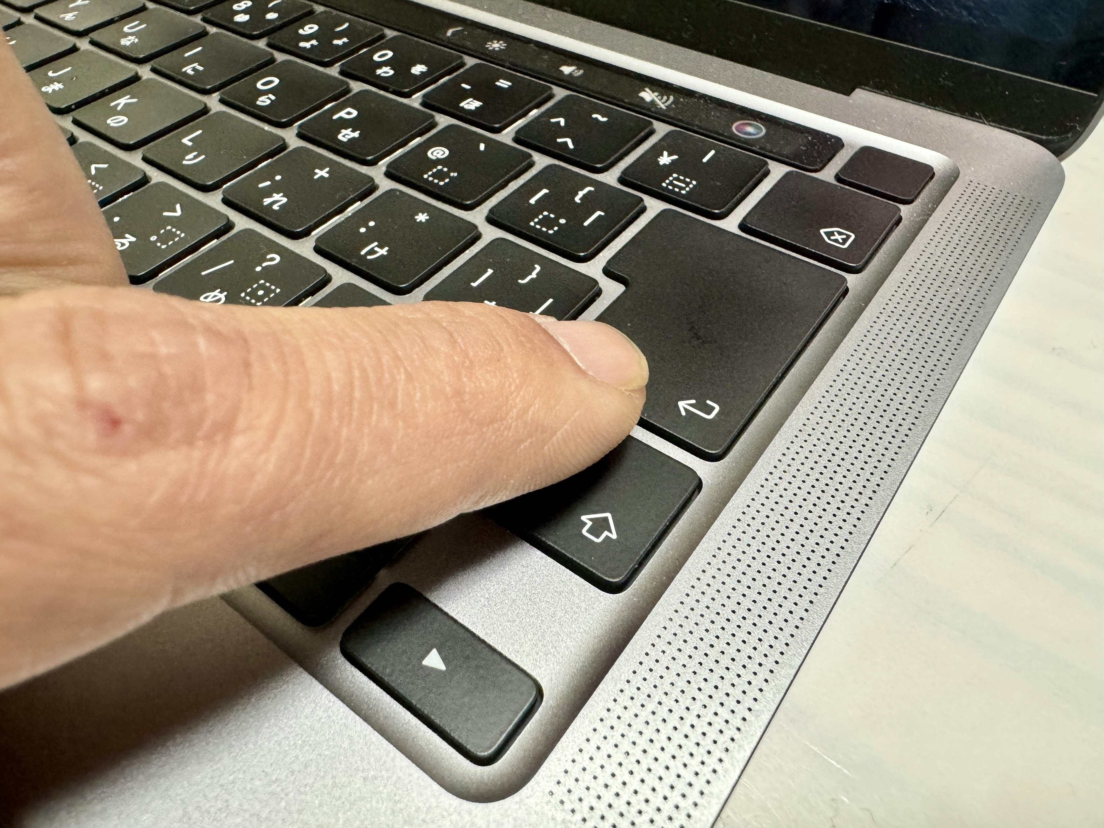 Close-up of a finger pressing a key on a silver keyboard