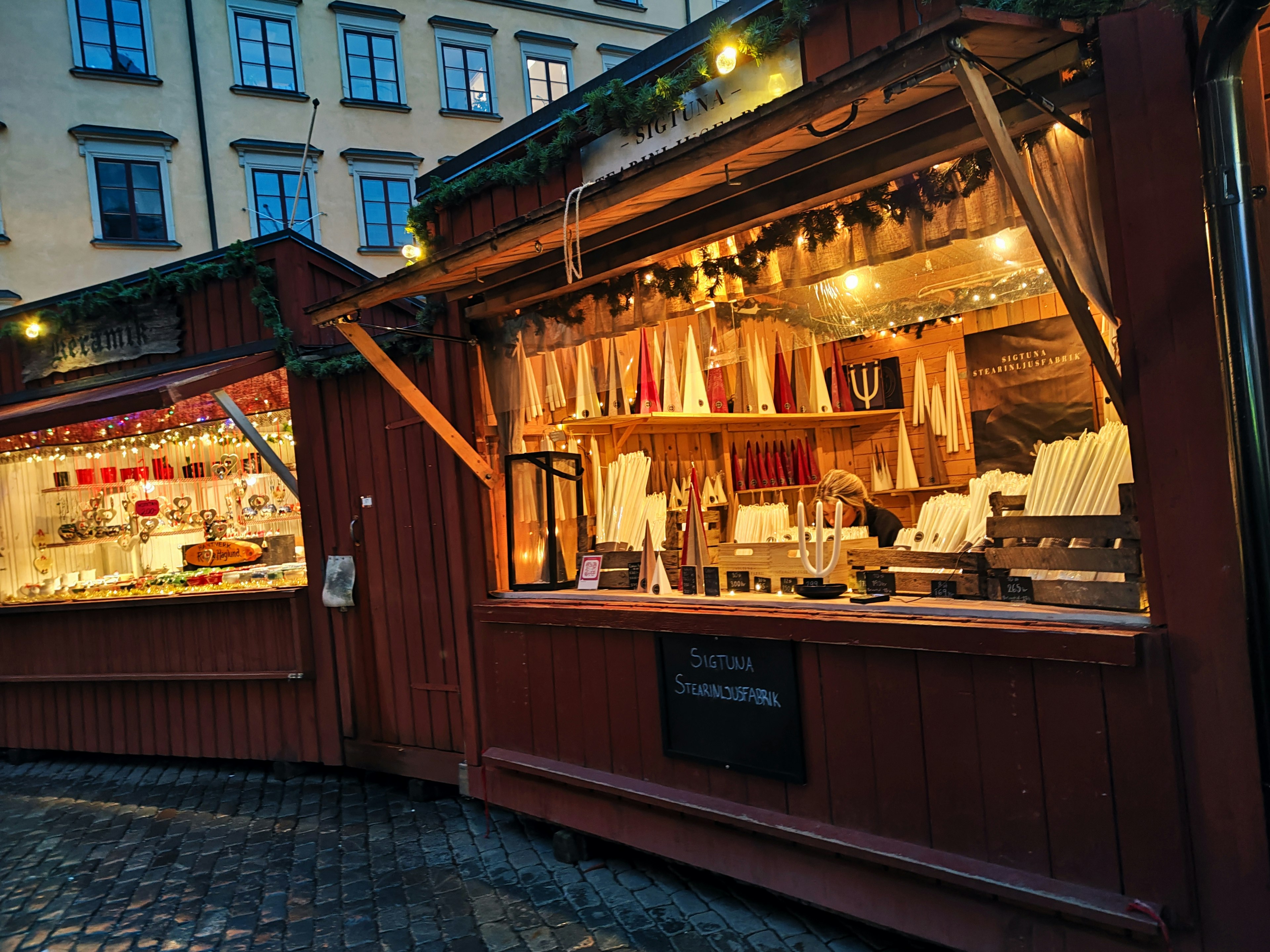 Scène de marché nocturne avec des étals en bois illuminés présentant des produits colorés