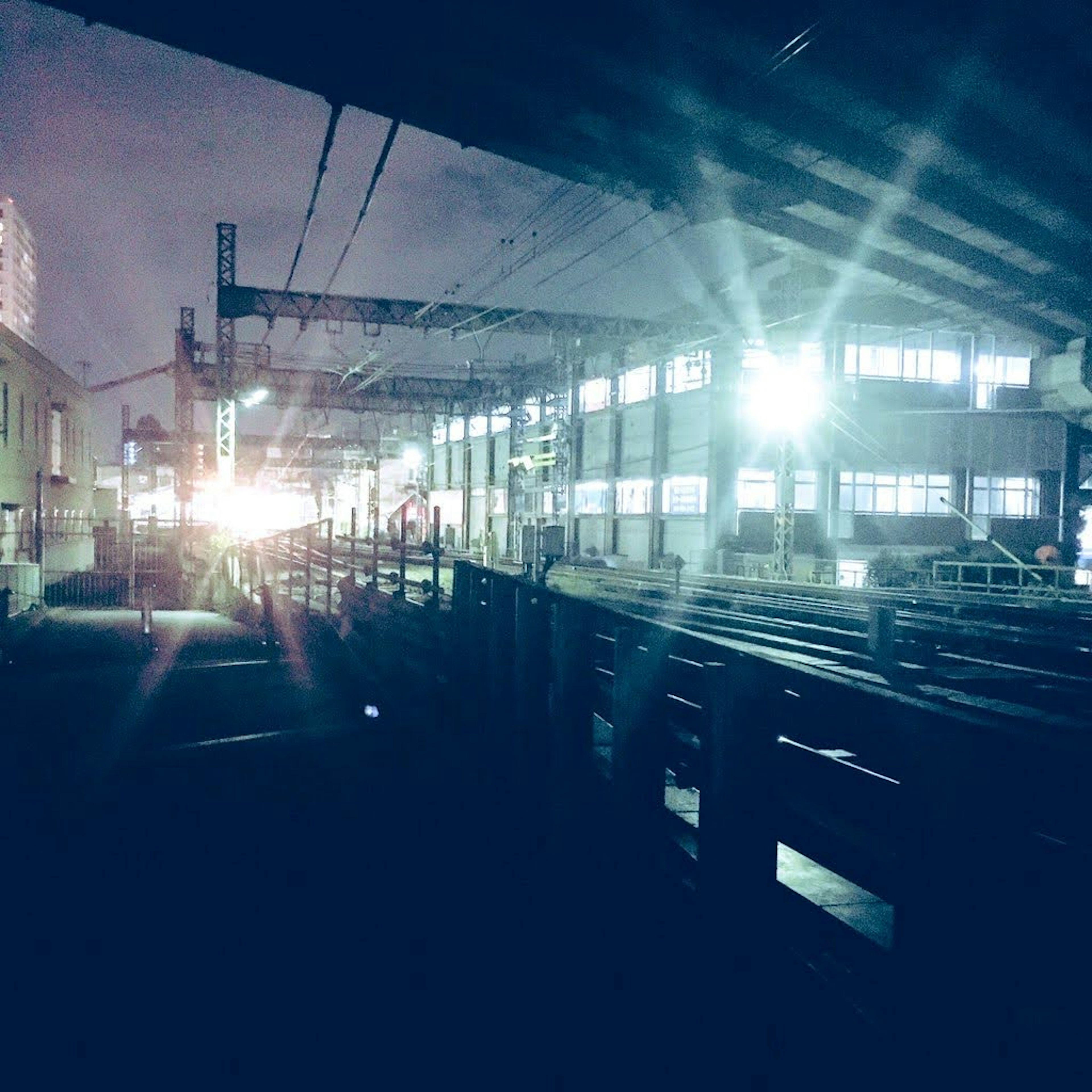 Interior of a factory at night bright lights and railway tracks