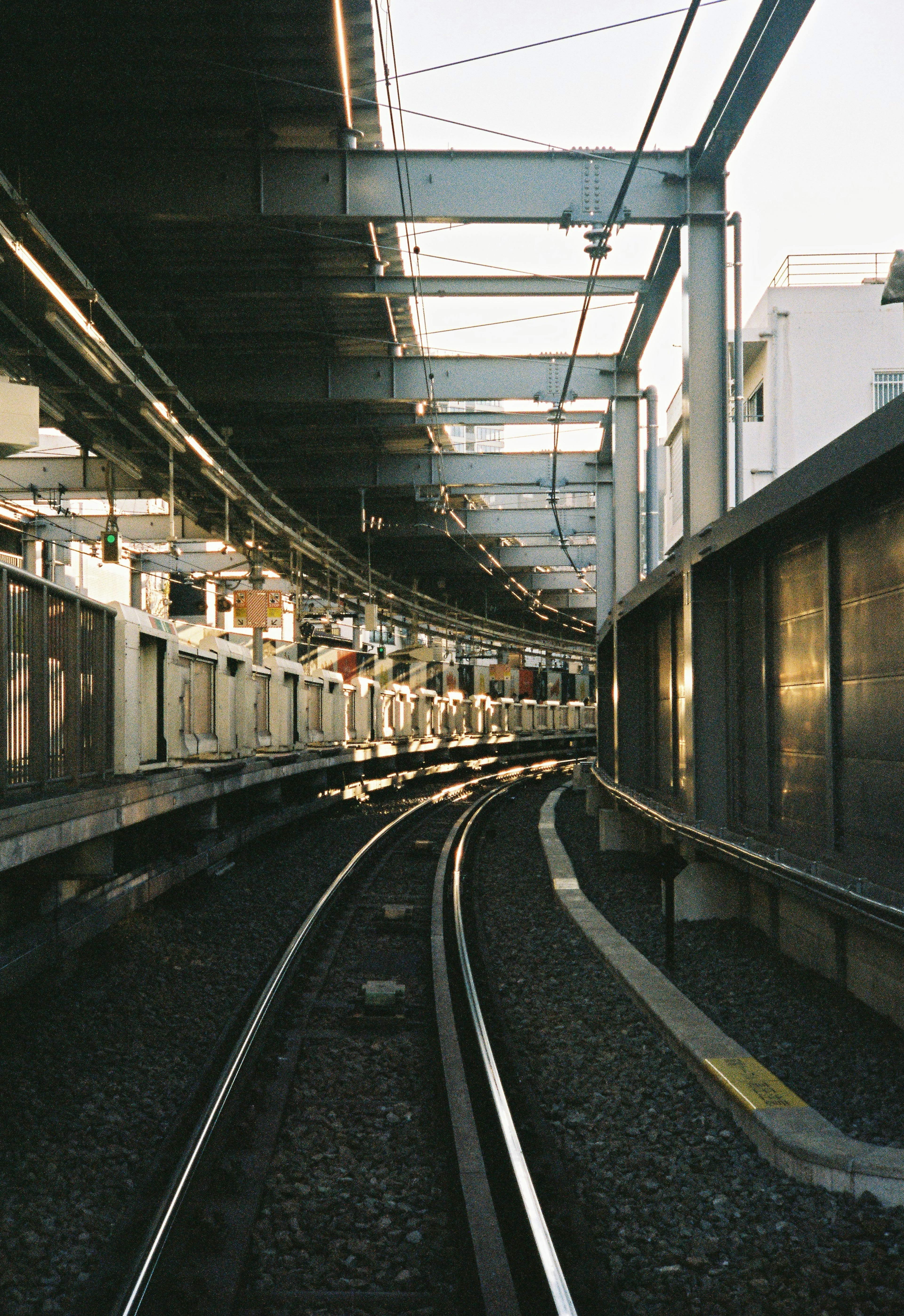 Binari ferroviari curvi sotto una struttura di stazione elevata