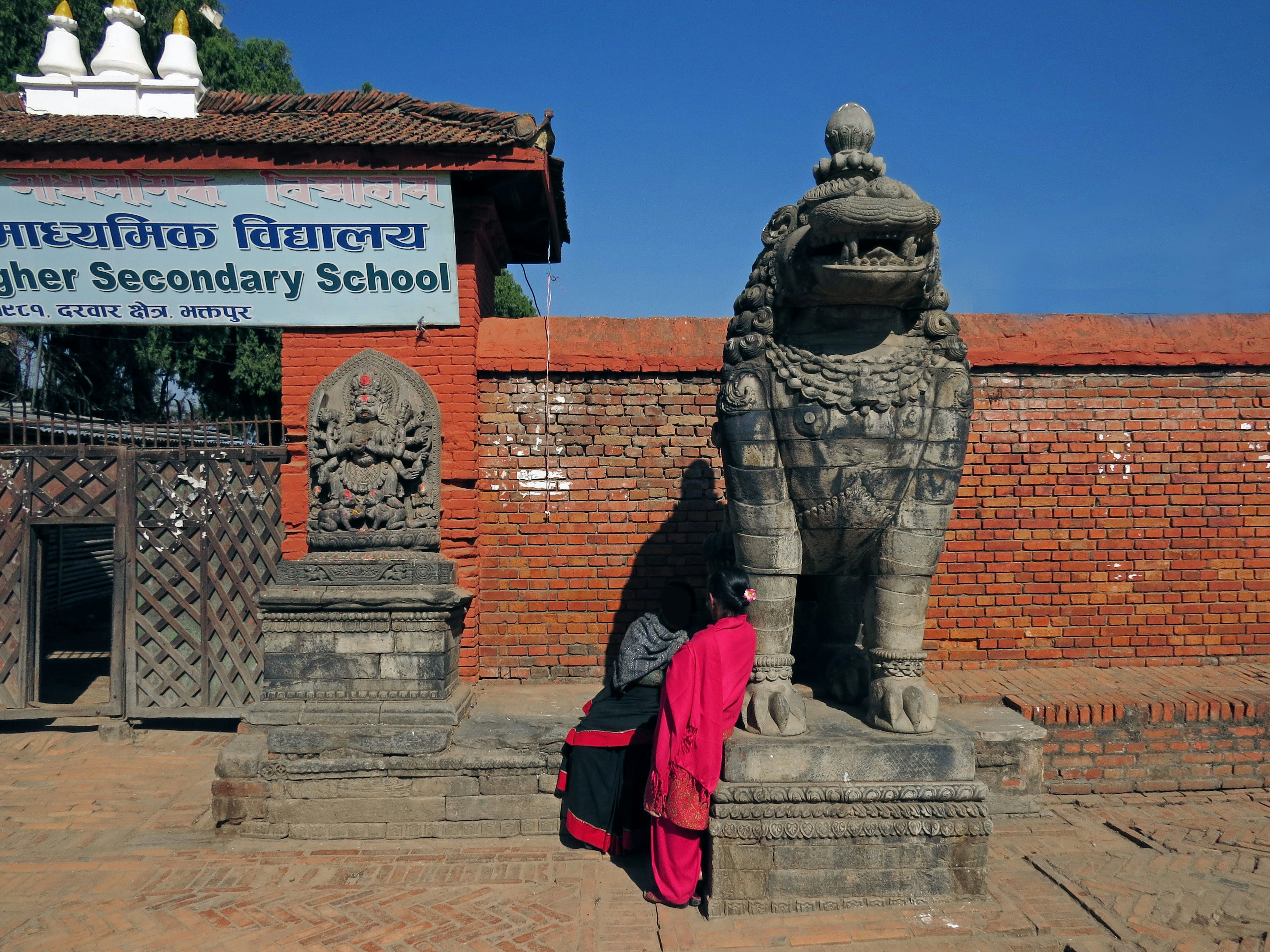 Statue de lion devant une école avec une personne en vêtements rouges