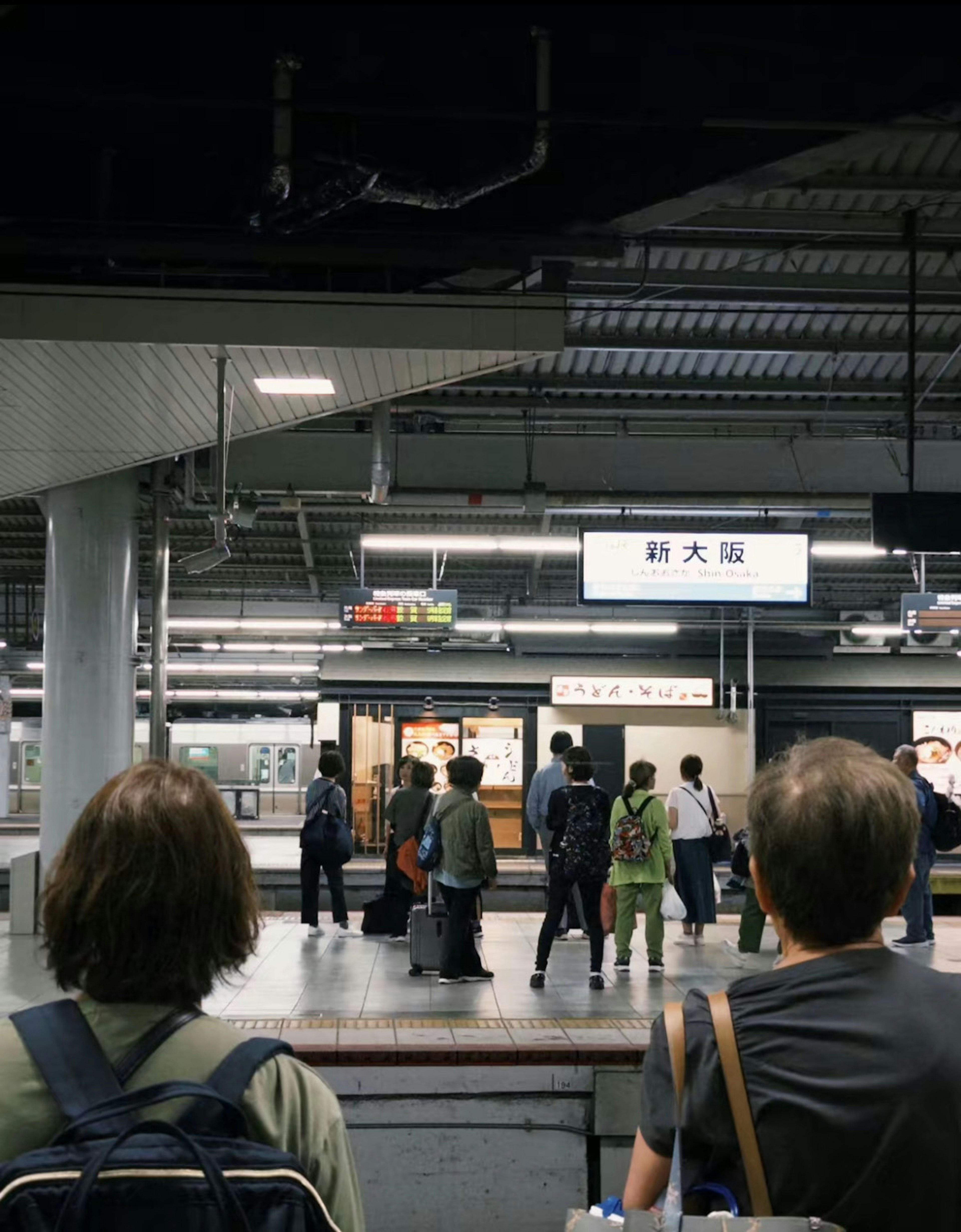 駅で待つ人々の風景 駅名の看板が見える