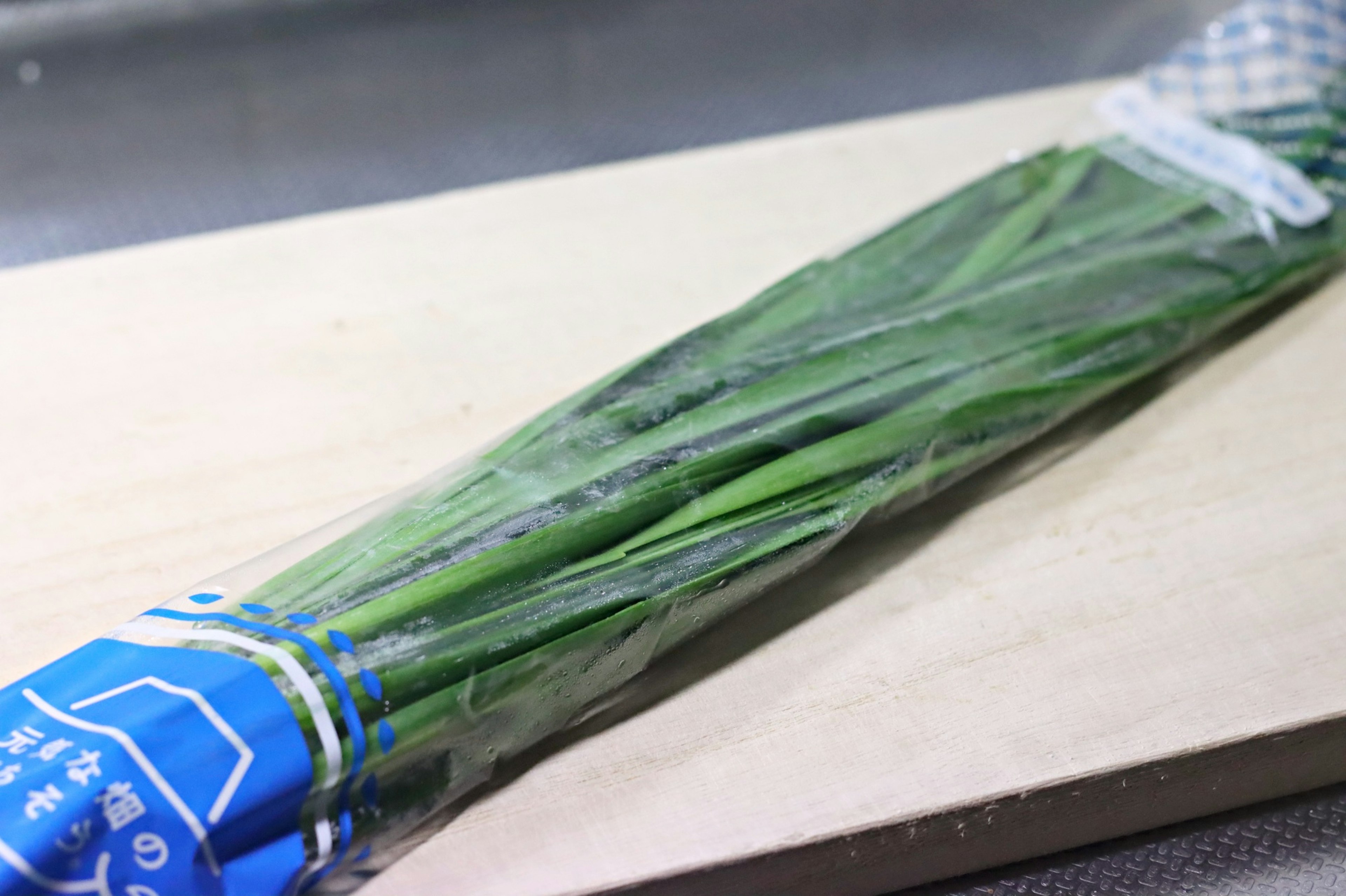 Packaged green onions placed on a wooden cutting board