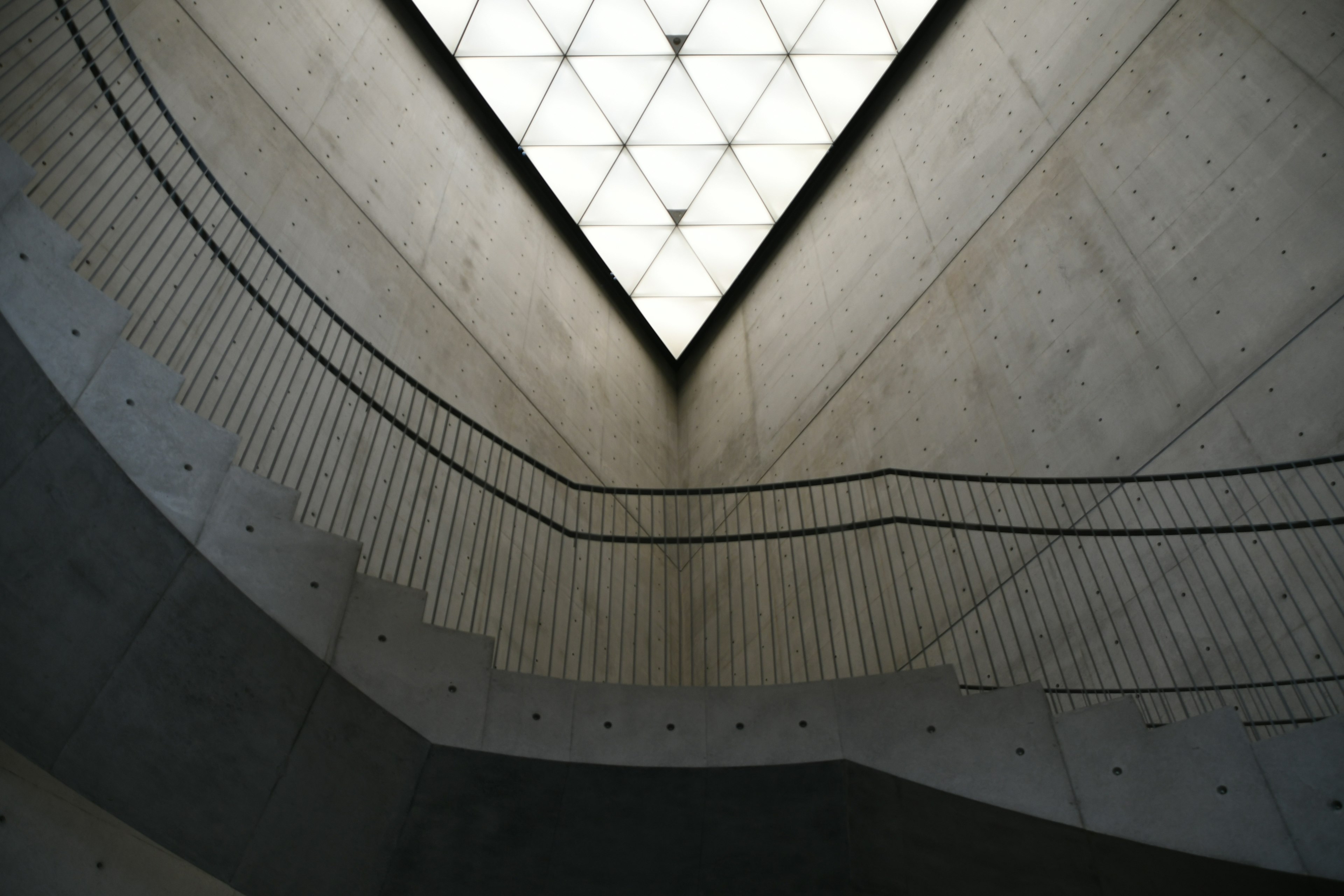 View looking up at a concrete staircase and bright ceiling